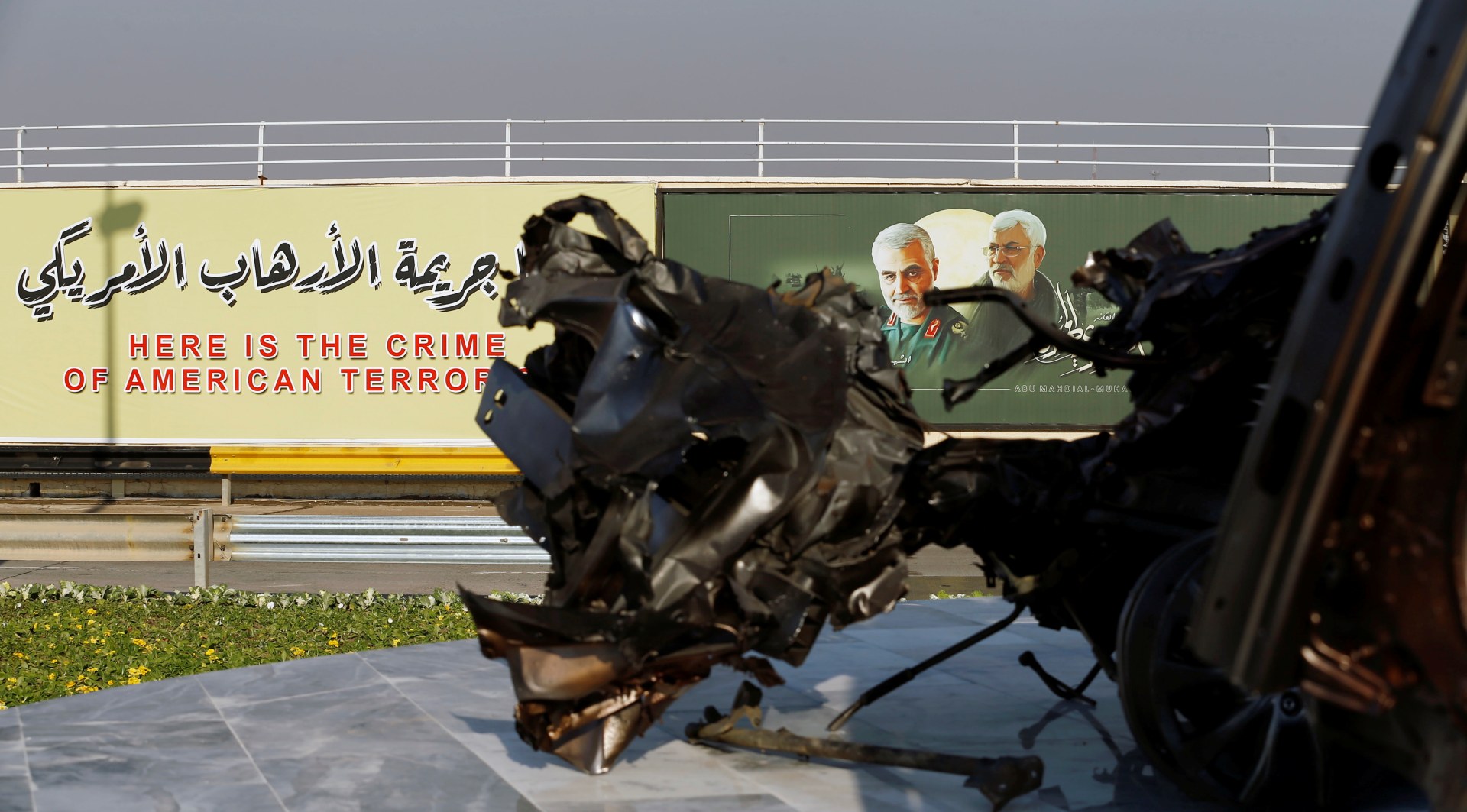 Pictures of Qassem Soleimani and Abu Mahdi al-Muhandis are seen near the remains of their destroyed vehicles in Baghdad airport (Reuters)