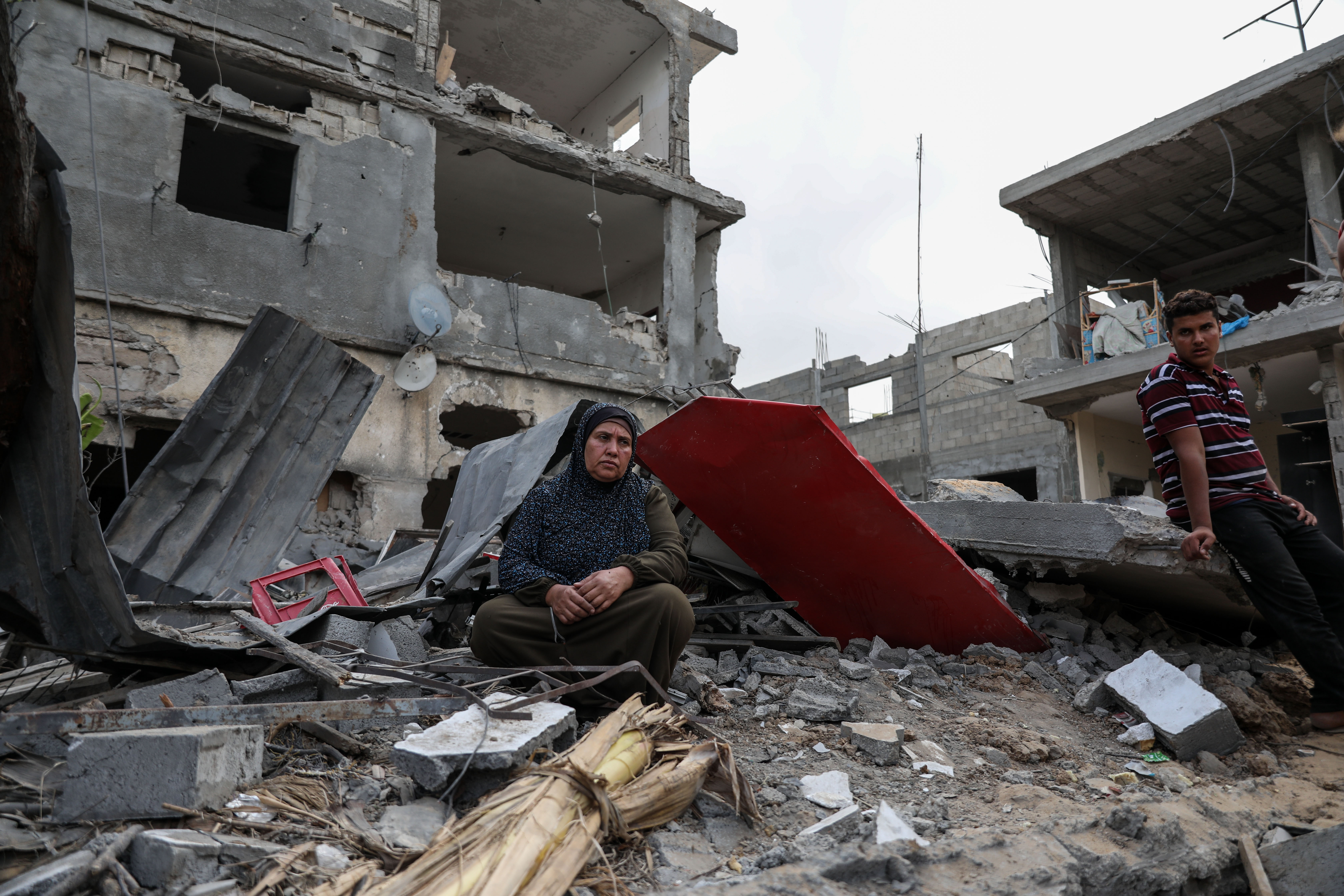 A woman sits in the demolished ruins of her home, which had been bombed by an Israeli air strike