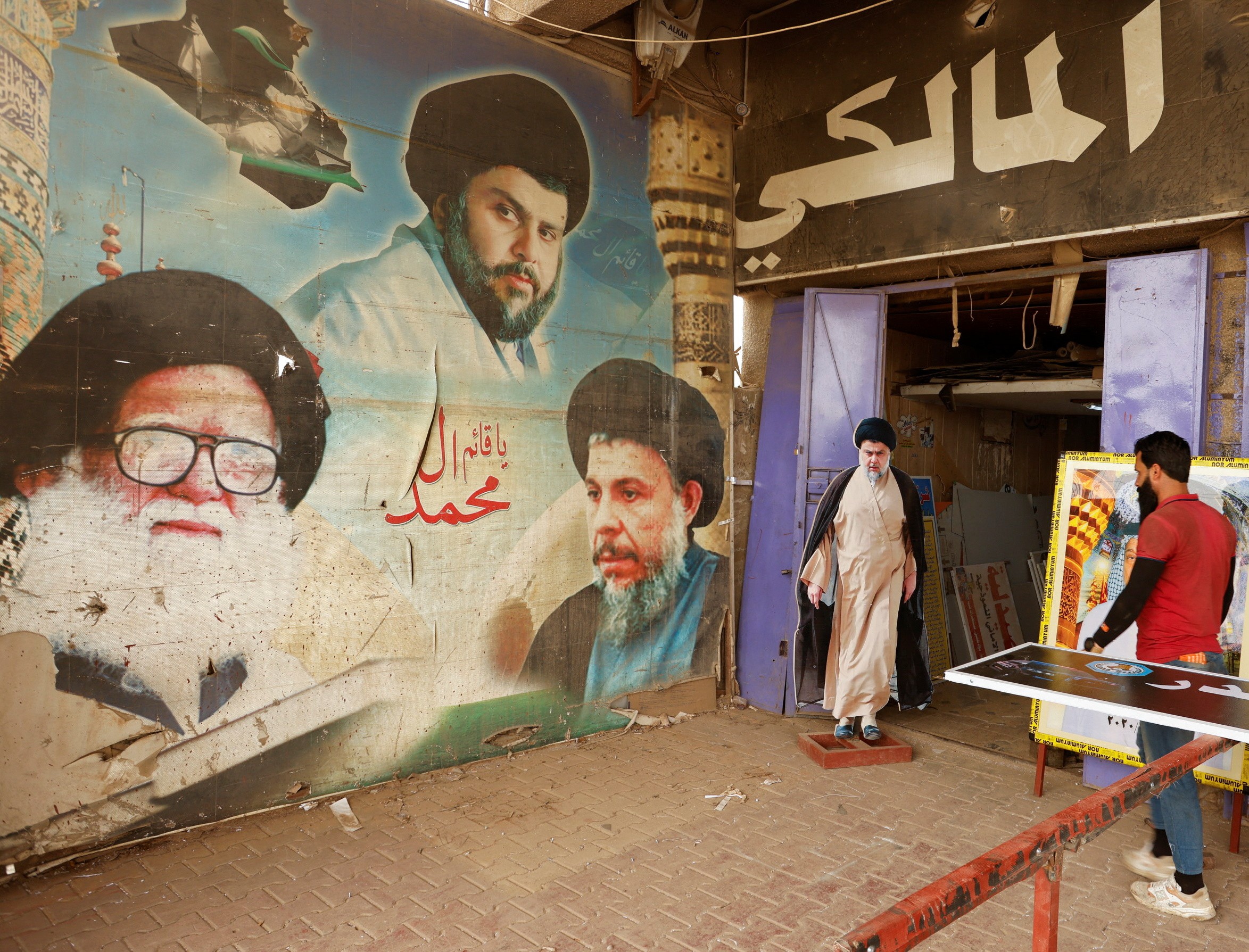 A man walks near a poster of Muqtada al-Sadr, in the Sadr City district of Baghdad (Reuters)