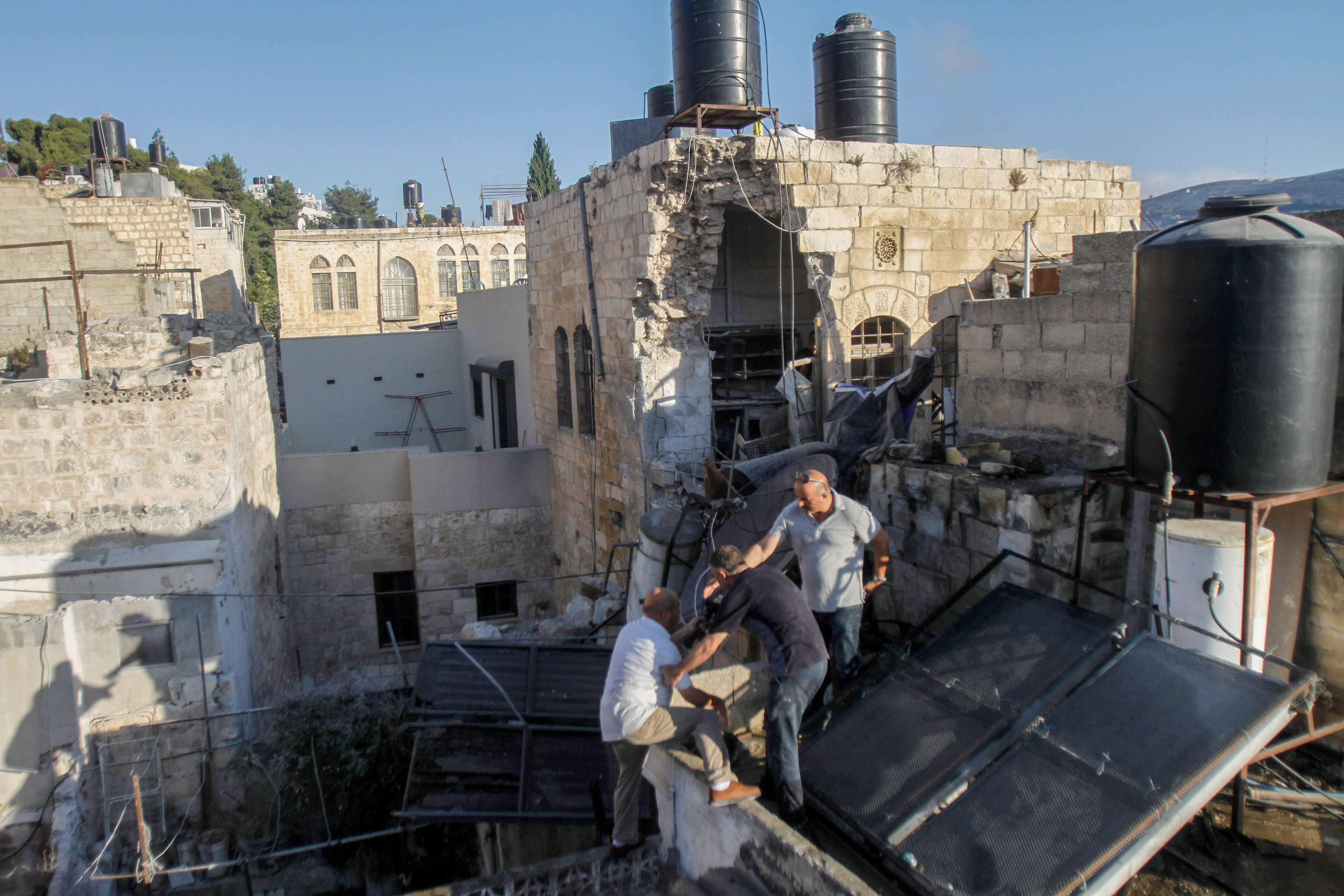 Palestinians inspect a damaged house that was bombed by the Israeli army during a raid in the Old City of Nablus in the occupied West Bank on 24 July 2022. (Reuters)