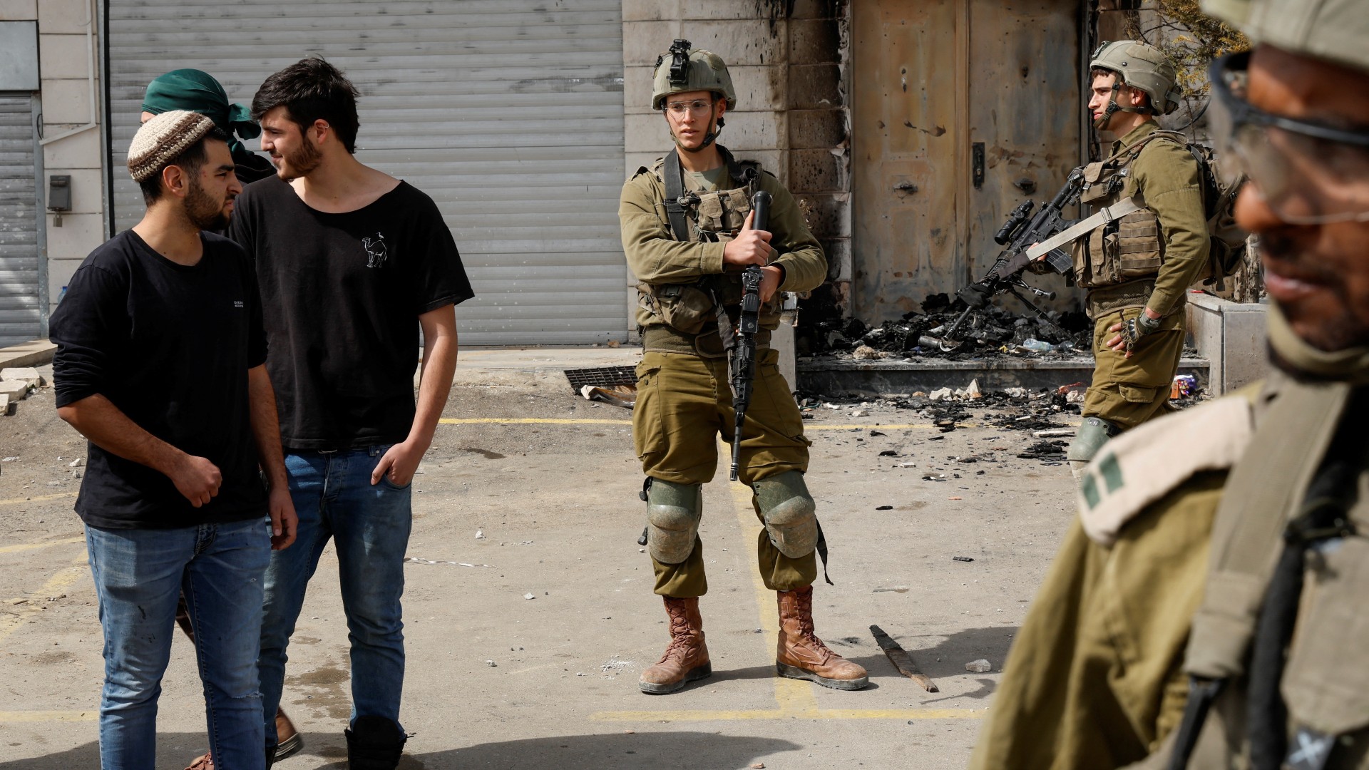 Israeli settlers stand next to Israeli soldiers near Huwwara on 27 February (Reuters)