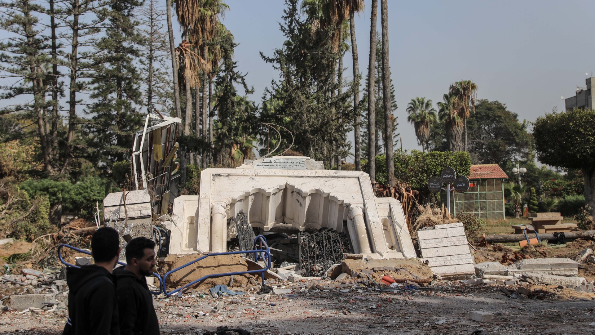 Palestinians walk past a park destroyed by Israeli air strikes in Gaza City on 24 November 2023 (MEE/Mohammed al-Hajjar)
