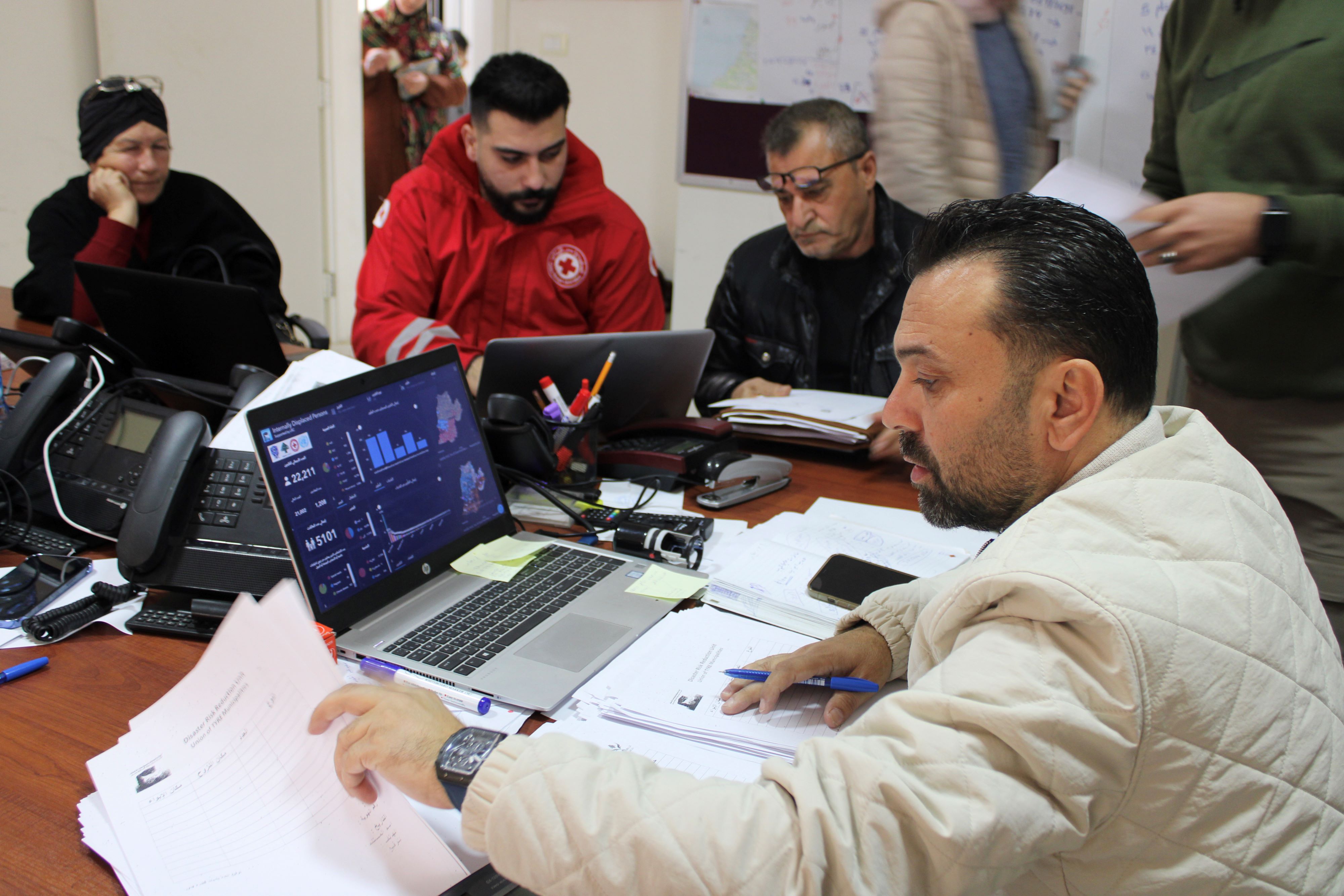 Mortada Mhanna and his team at the Disaster Management Union office building in Tyre work to register displaced families for food baskets (Hanna Davis/ MEE)