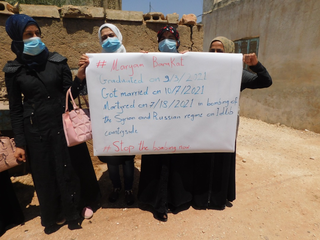 A group of woman hold a banner in Idlib summarising Barakat's short life (Twitter)