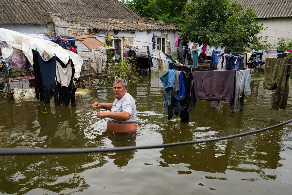 Un homme dans le jardin inondé de sa maison dans la région de Mykolaïv, après la destruction du barrage de Kakhovka, le 10 juin 2023 (AFP)