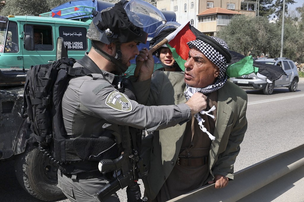 A member of the Israeli security forces scuffles with a protester as Palestinian and Israeli peace activists demonstrate at the entrance of Huwwara in the occupied West Bank, 3 March 2023 (AFP)