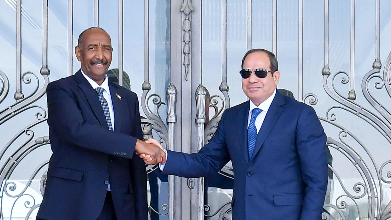 Egyptian President Abdel-Fattah el-Sissi, right, greets Sudan's army chief General Abdel Fattah al-Burhan at the Presidential palace in el-Alamein city, Egypt 29 August (AP)