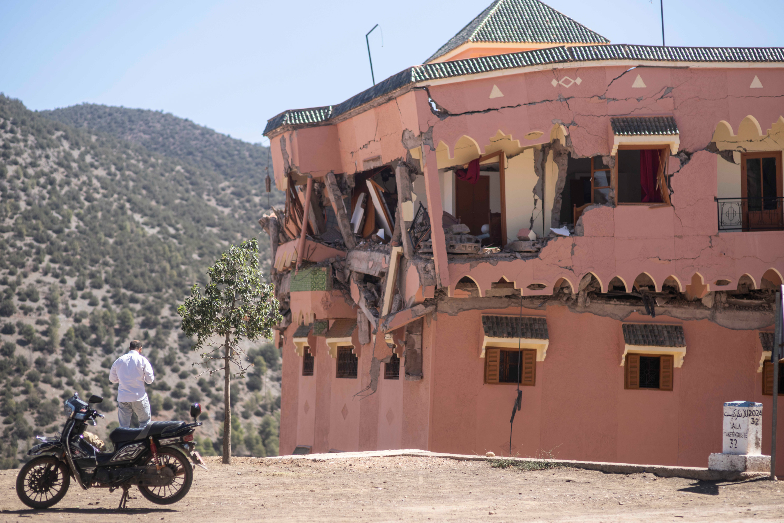 A man stands next to a damaged hotel after the earthquake in Moulay Brahim village, near the epicentre of the earthquake, outside Marrakech on 9 September 2023 (AP)