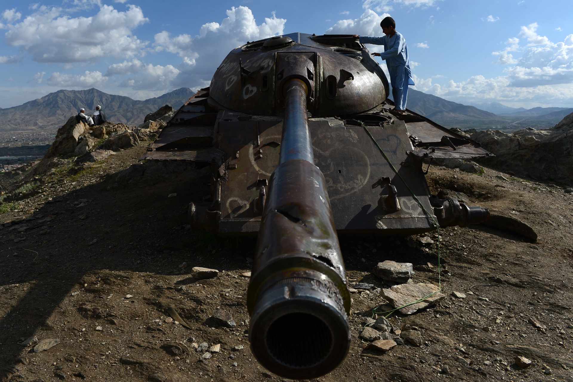 Afghan youths climb on the wreck of a Soviet tank in Afghanistan in 2014 (AFP)