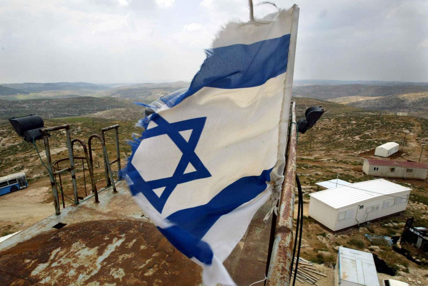 Un drapeau israélien flotte devant la colonie d’Asael au sud d’Hébron, en Cisjordanie occupée, le 28 avril 2003 (AFP)