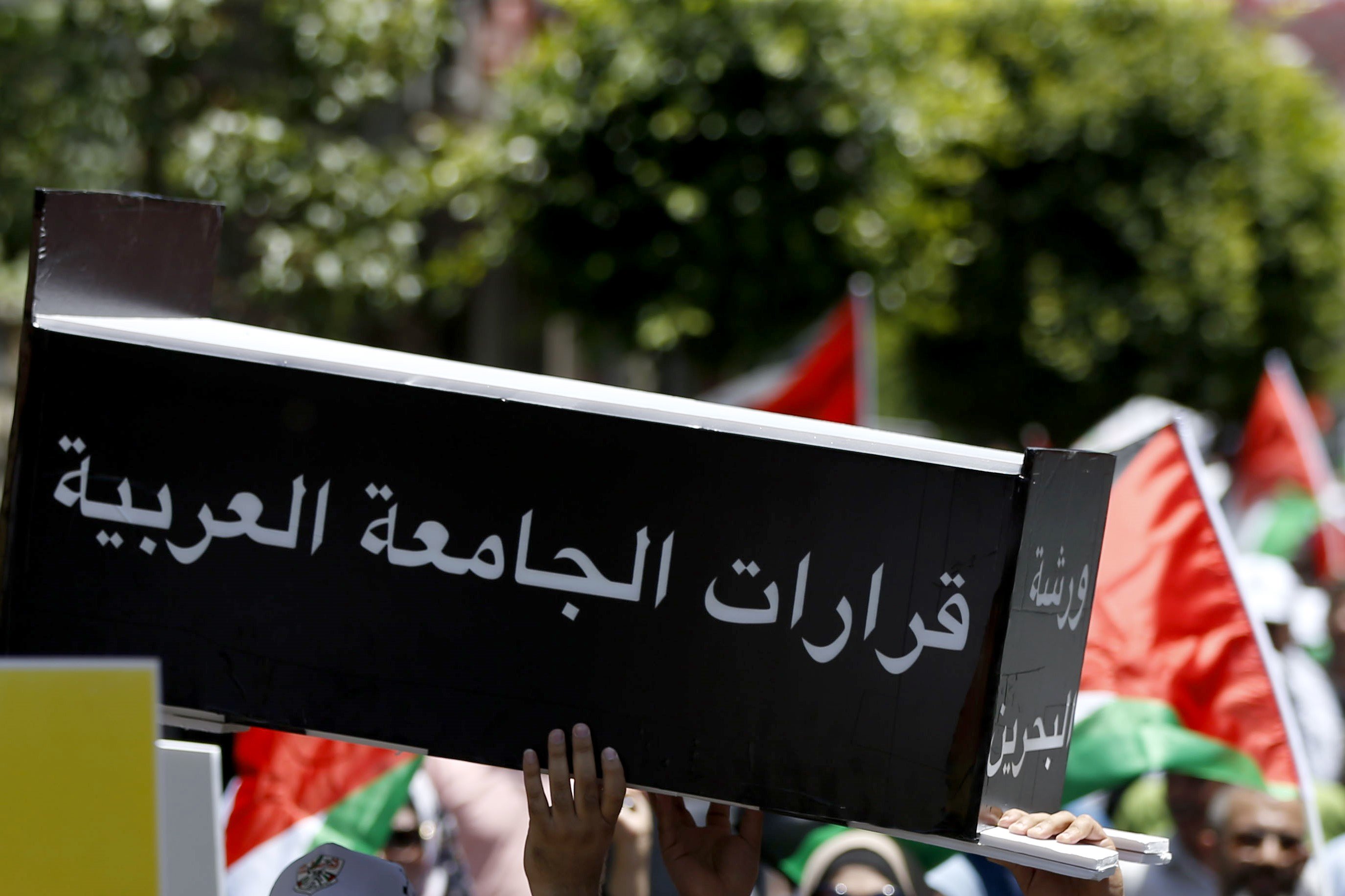 Des manifestants palestiniens portent un cercueil de fortune comportant l’inscription « Les décisions de la Ligue arabe » (AFP)