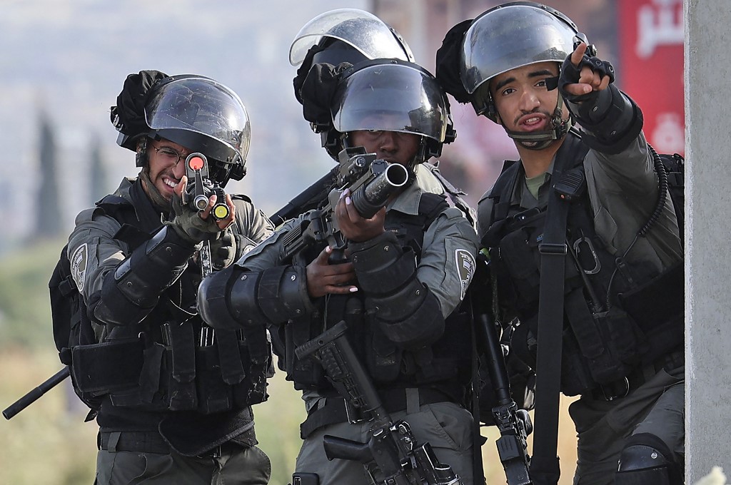 Israeli border guards take aim at Palestinian protesters following the nationalist 'flag march' through Jerusalem, at the Israeli-controlled Huwara checkpoint near Nablus, 29 May 2022 (AFP)