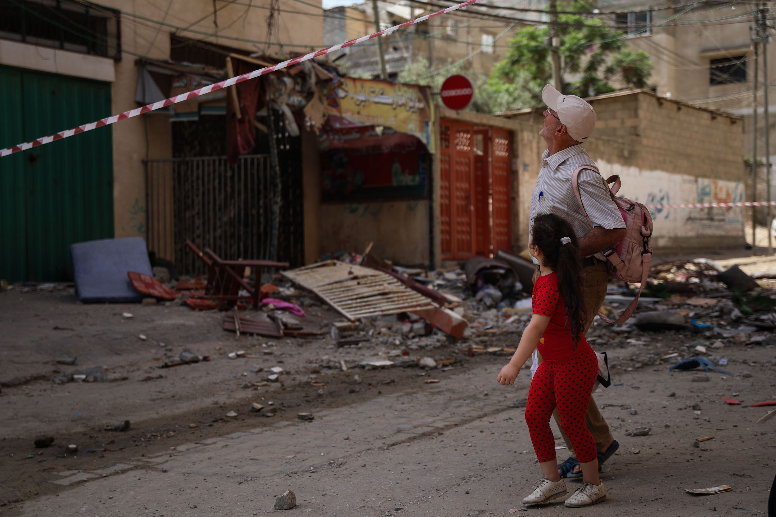 Man and child looking at buildings damaged in Gaza attack / MEE
