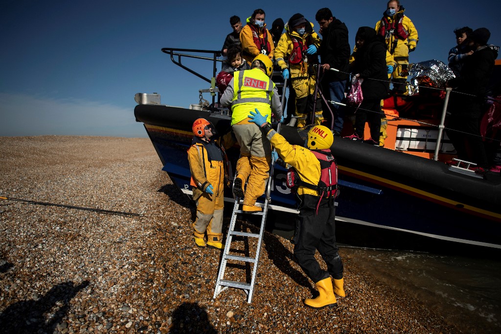 People picked up at sea attempting to cross the English Channel are helped ashore from a lifeboat at Dungeness on the English southeast coast, 15 March 2022 (AFP)