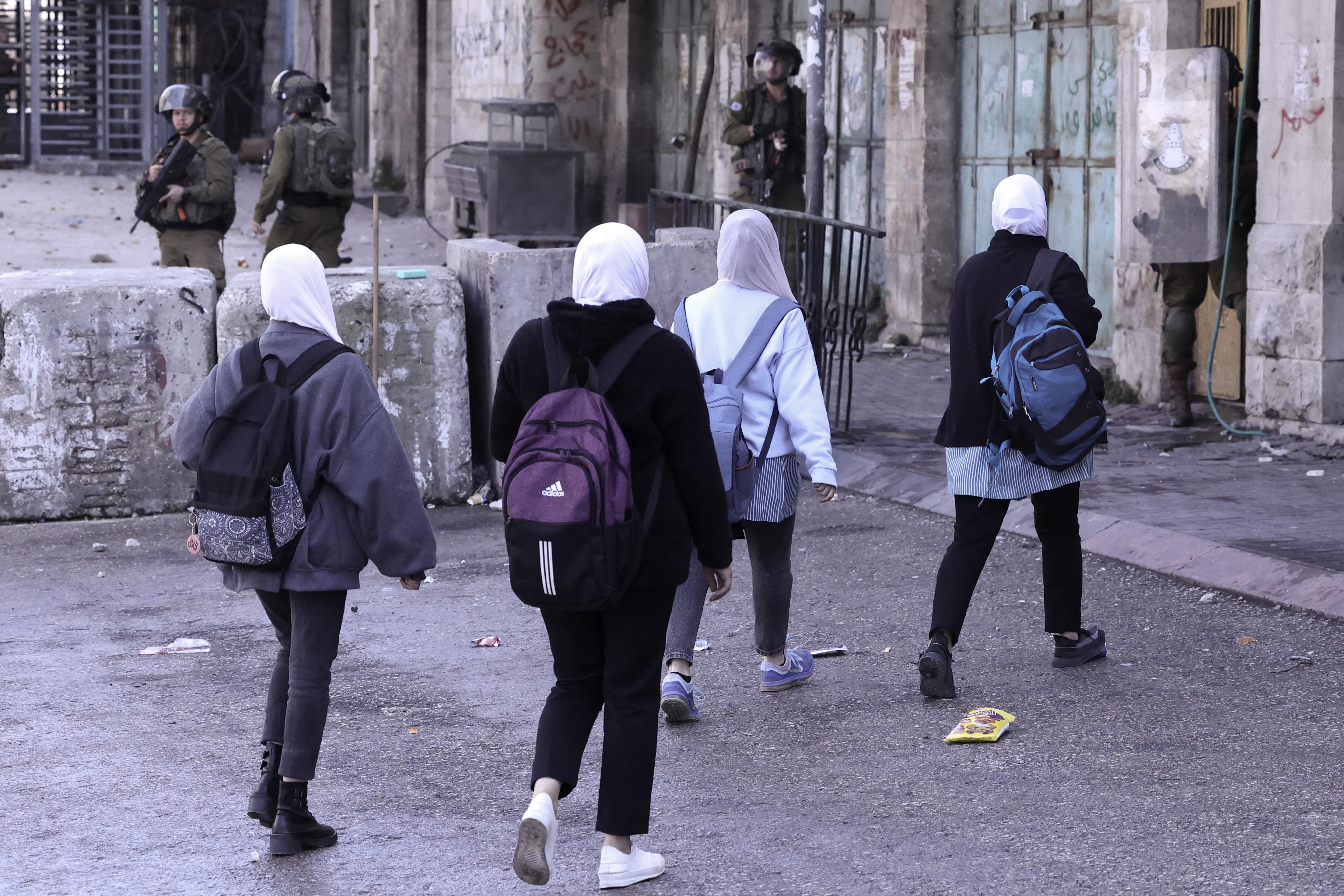 Palestinian students walk as Israeli forces crackdown on protests in Hebron on 2 March 1, 2022 (Afp)