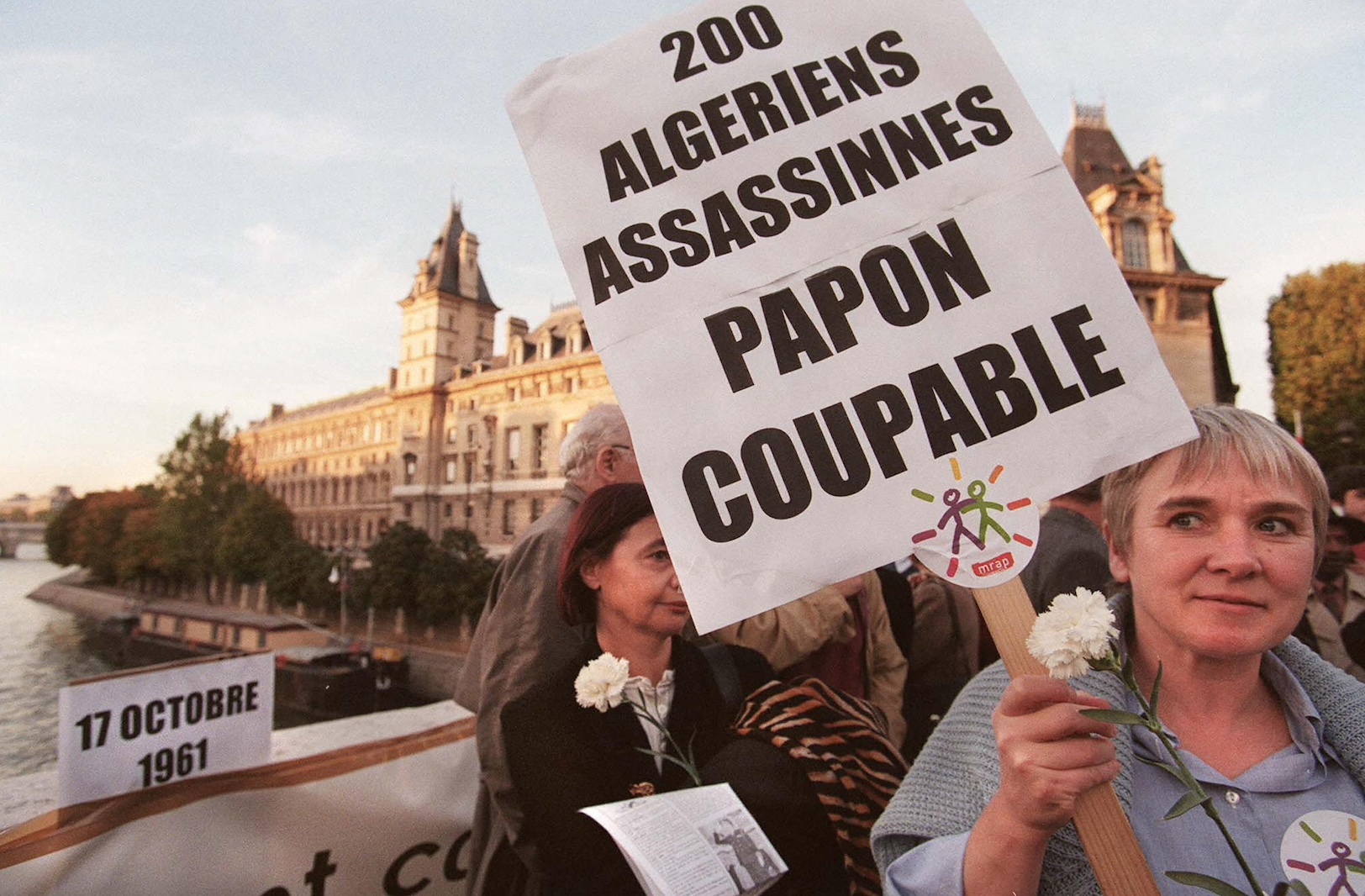 Une femme porte une pancarte, le 17 octobre sur le Pont Saint-Michel à Paris, lors d’un rassemblement en souvenir des Algériens tués par la police lors d’une manifestation le 17 octobre 1961 (AFP)