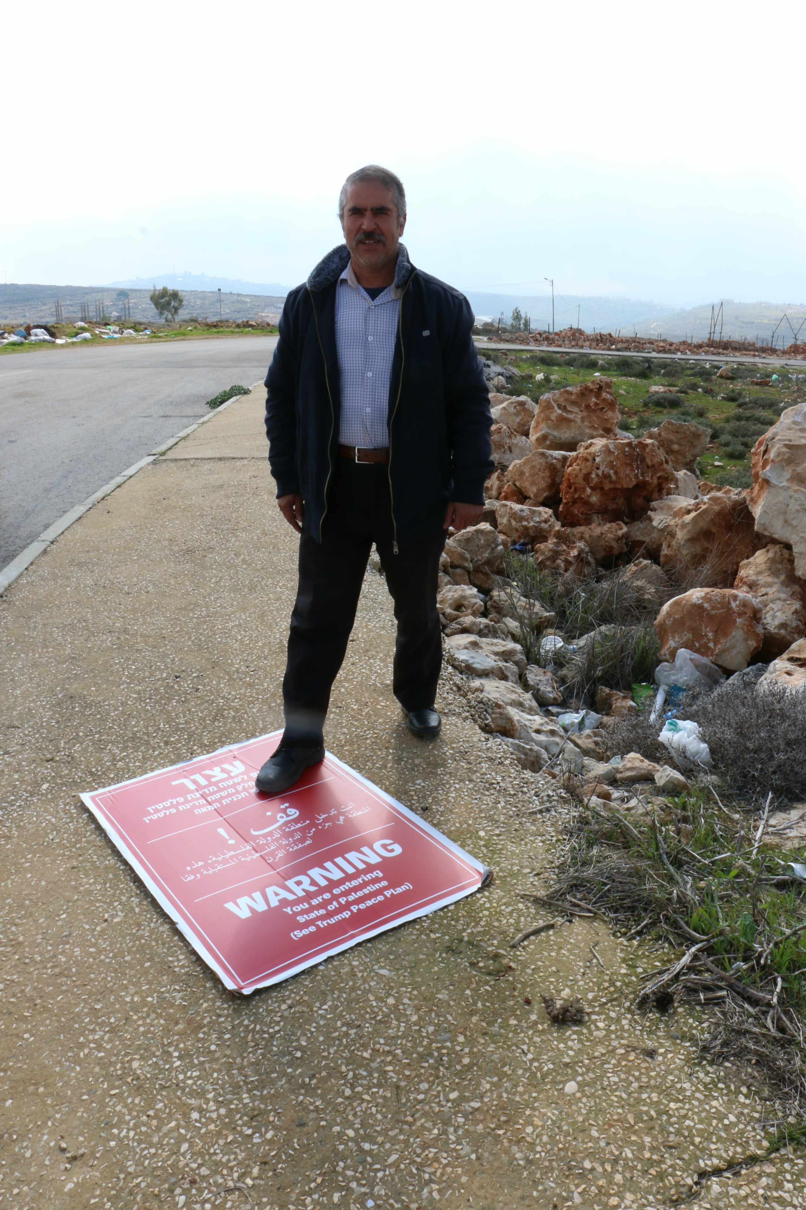 A resident of the village of Qusra steps on a Regavim sign (MEE/Akram al-Waara)