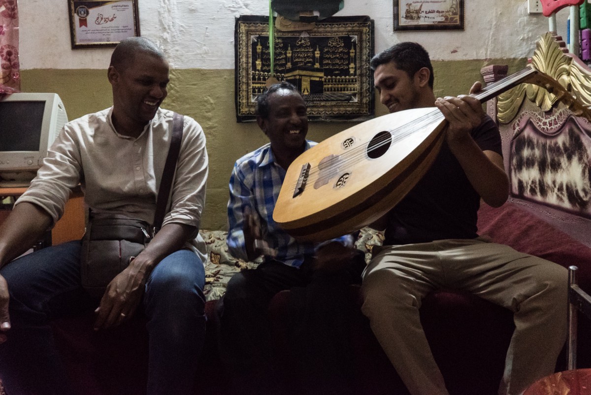 فيك سوهوني (إلى اليمين) ، مؤسس شركة Ostinato Records ، ومنسق المشروع أحمد أسيوطي (إلى اليسار) خلال لقاء مع المطرب عماد يوسف في منزله بالخرطوم عام 2017 (جانتو دجاسي)