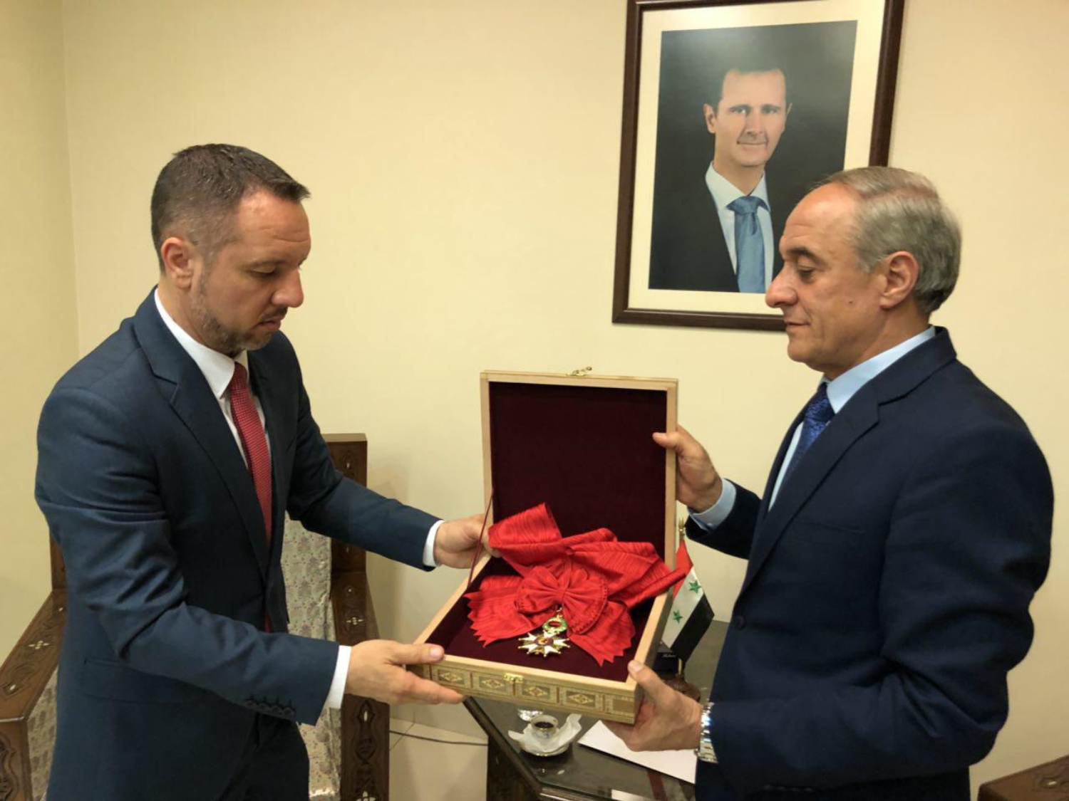 A handout picture released on the Syrian President Facebook page on 19 April 2018 shows a representative of Syria's foreign affairs returning France's grand cross of the legion of honour (AFP)