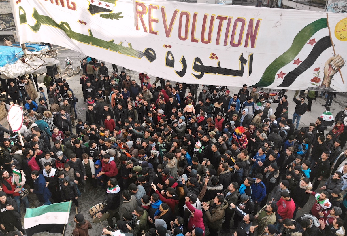 Des Syriens tiennent une bannière sur laquelle on peut lire en arabe : « La révolution continue », dans la province d’Idleb, le 10 janvier 2020 (AFP)