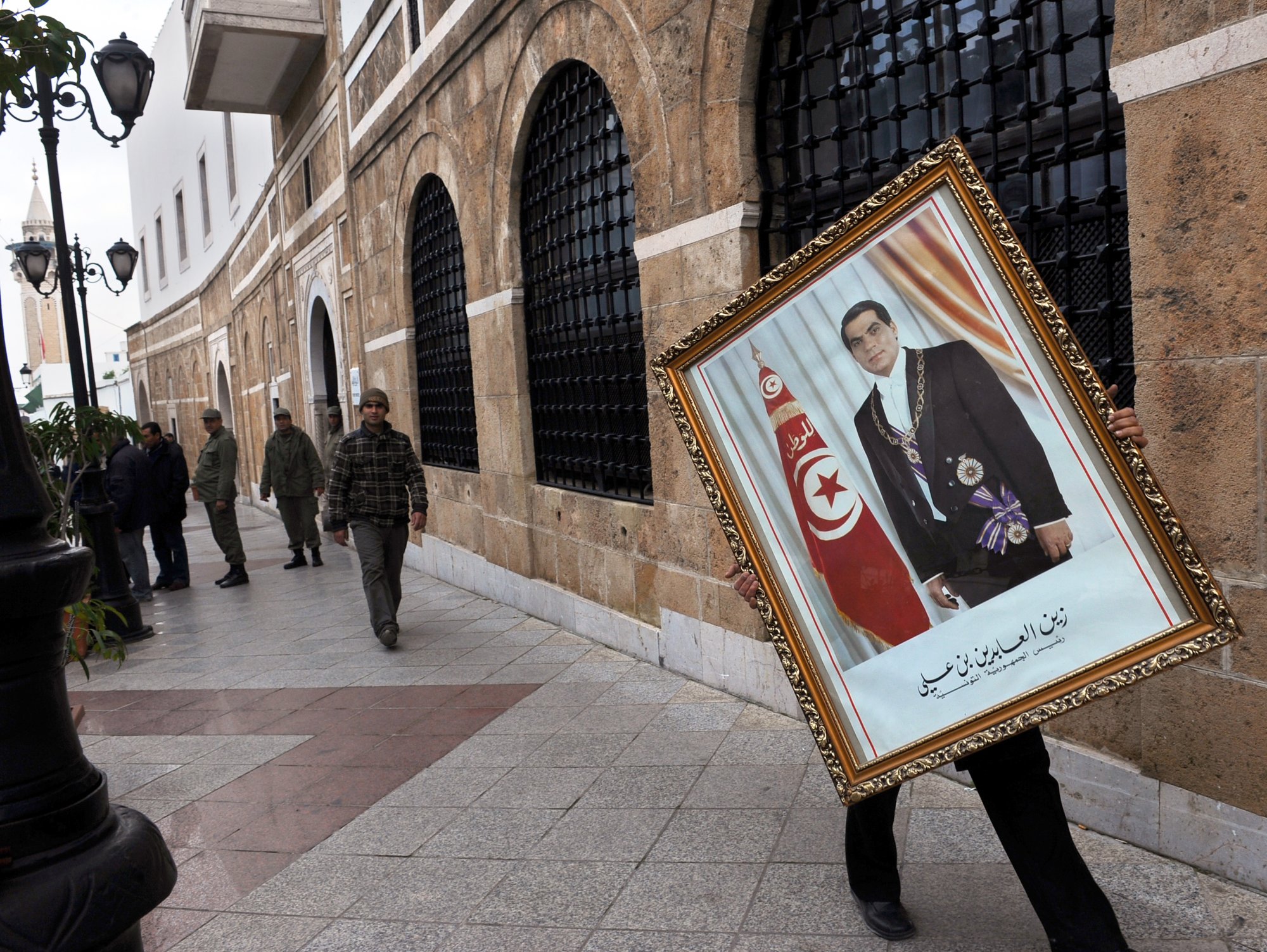 A Tunisian employee of the prime ministry removes a portrait of former Tunisian President Zine El Abidine Ben Ali on 17 January 2011 (AFP)