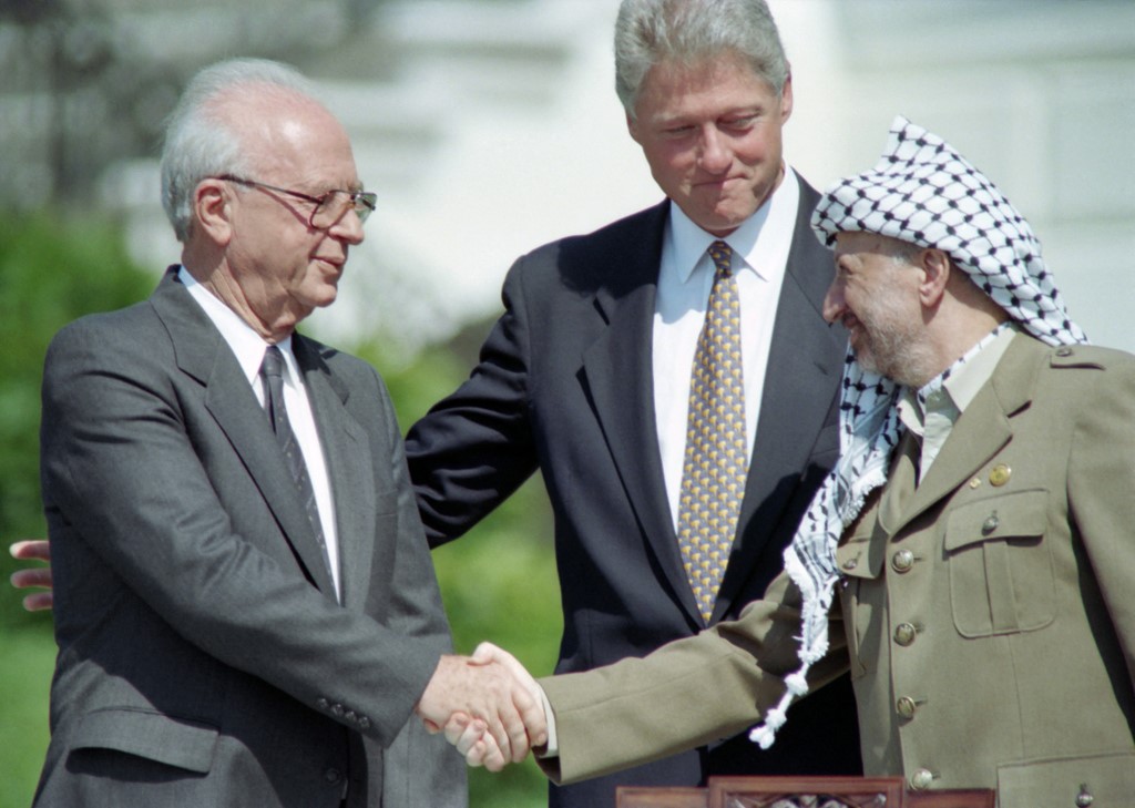 US President Bill Clinton (C) with PLO leader Yasser Arafat (R) and Israeli Prime Minister Yitzhak Rabin (L), as they shake hands after signing the Oslo Accords at the White House, 13 September 1993 (