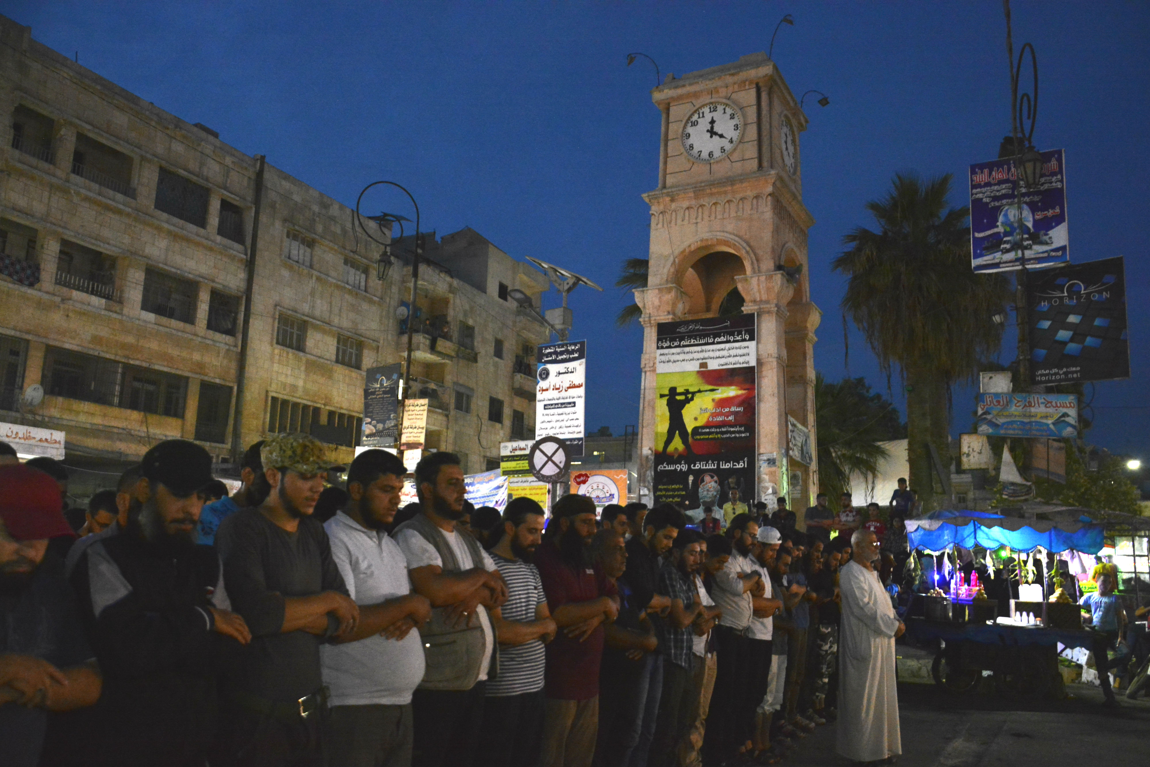 Syrians gather below Idlib city's clock tower to perform funeral prayers for Abu al-Zein al-Homsi (MEE/Harun al-Aswad)