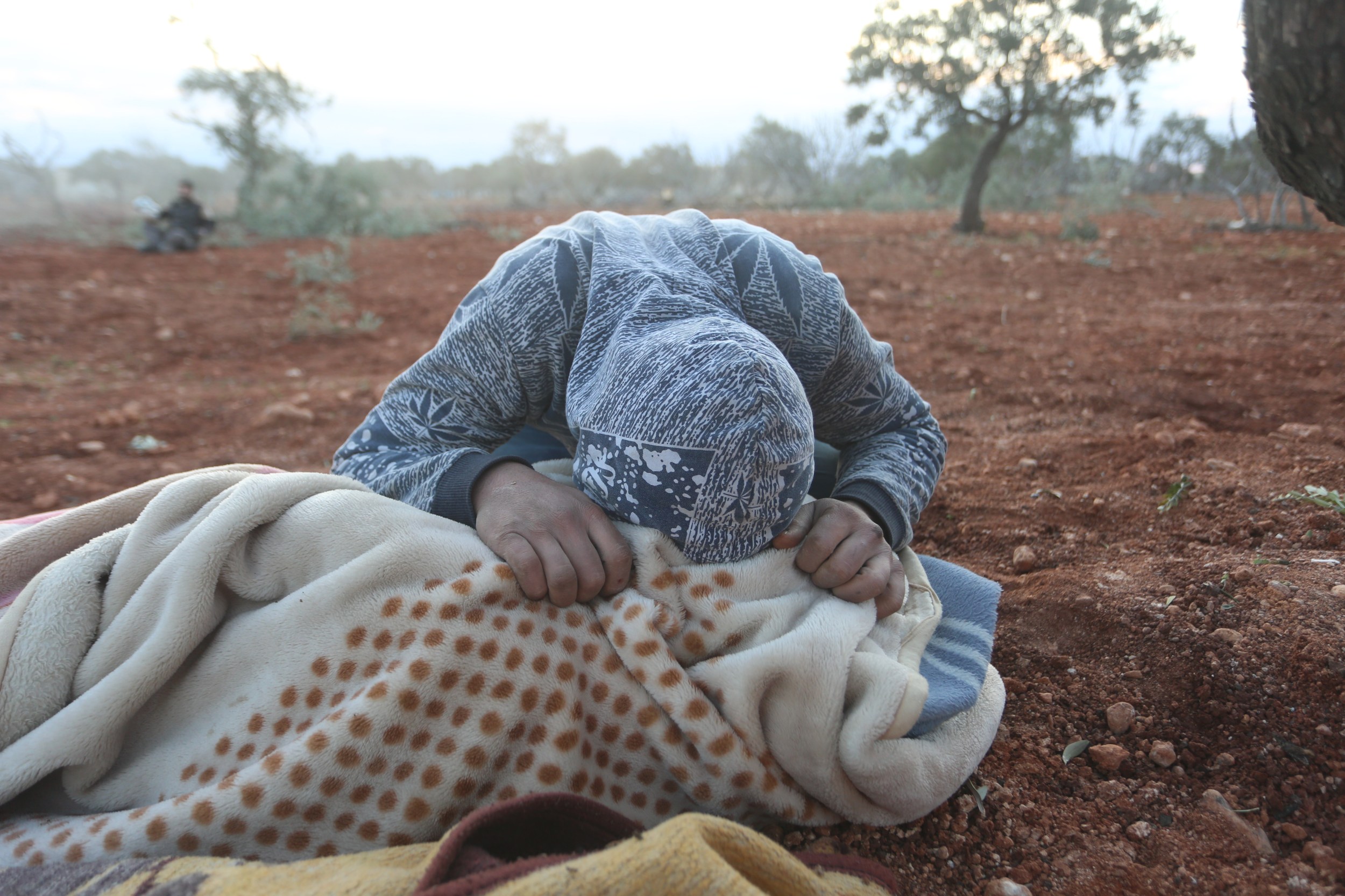 A young Syrian mourns over the body of a relative killed in an air strike in Sarmeen in the eastern Idlib province on 2 February 2020 (MEE/Ali Haj Suleiman)