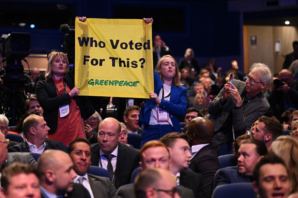 Activists hold a banner criticising Truss’s premiership at the Tory party conference in Birmingham on 5 October 2022 (AFP)
