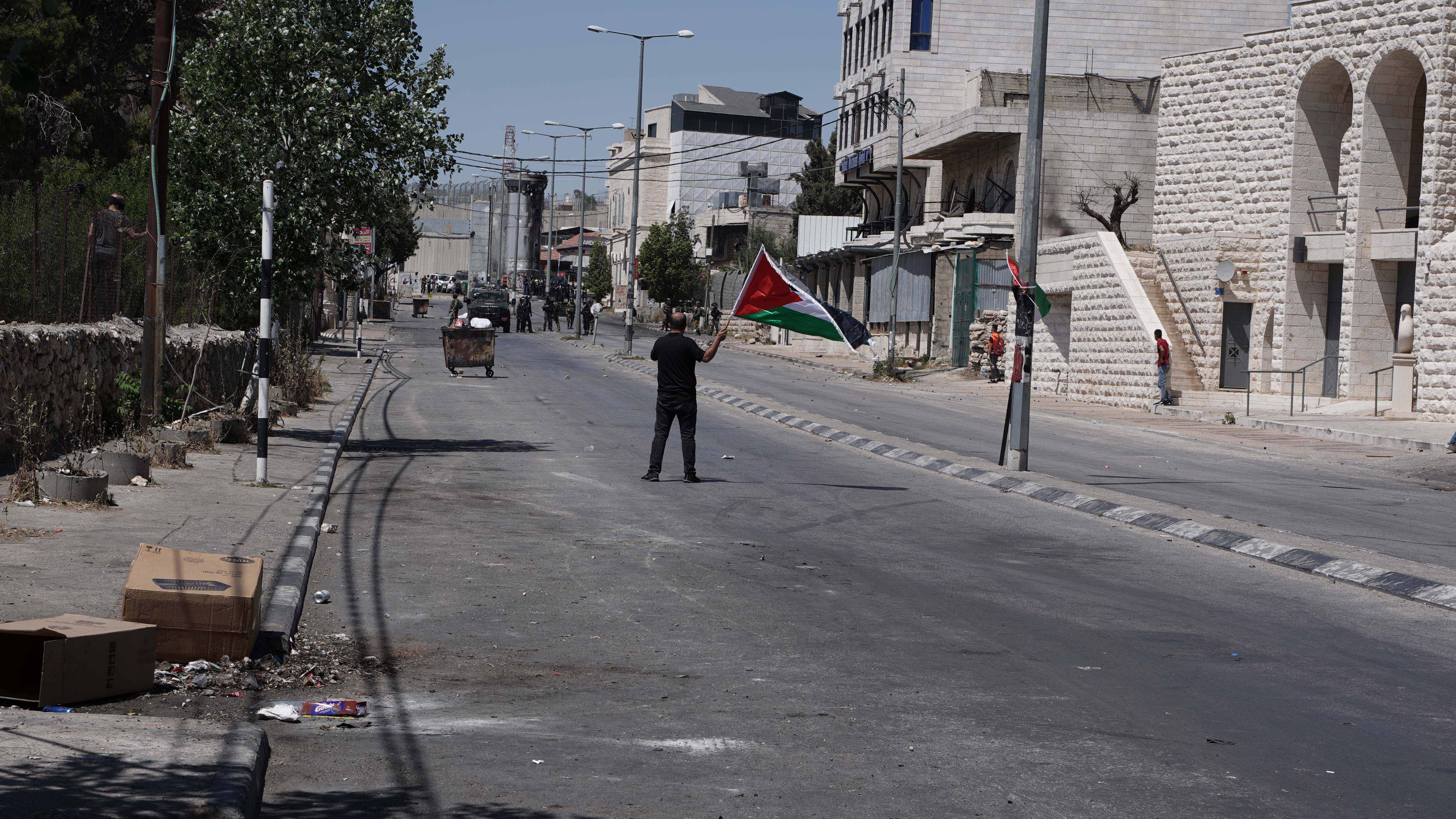 A man waves a Palestinian flag in front of a group of Israeli forces in Bethlehem.