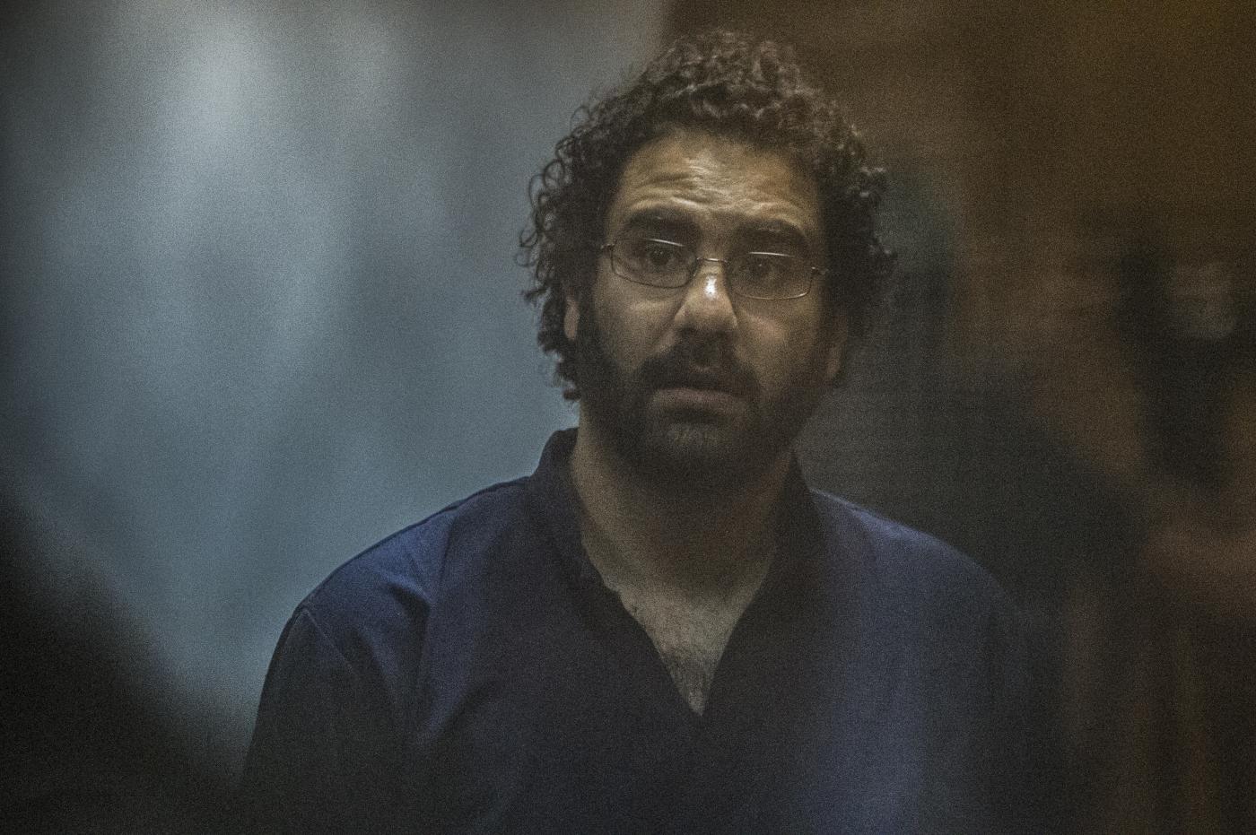 Egyptian activist and blogger Alaa Abdel Fattah looks on from behind the defendant's cage during his trial for insulting the judiciary alongside 25 other defendants including ousted Egyptian president Mohamed Morsi, who was recently sentenced to death, in Cairo on May 23, 201