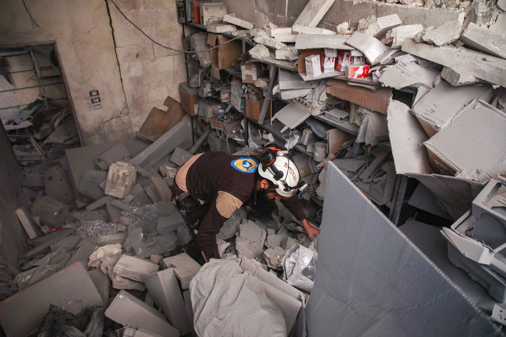 A member of the White Helmets searches for survivors at a destroyed hospital northwest of Aleppo on 17 February (AFP)