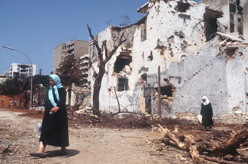 Lebanese women walk along a Beirut street devastated by Israeli shelling in 1982 (AFP)