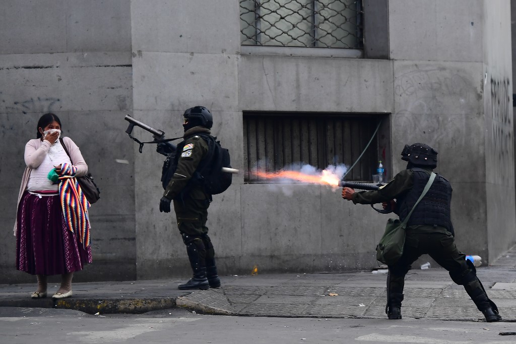 Bolivian riot police fire tear gas to disperse supporters of Morales, and locals discontented with the political situation, in La Paz on 13 November (AFP)