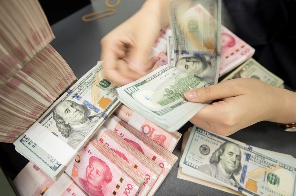 A Chinese bank employee counts yuan notes and US dollars in Jiangsu in 2019 (AFP)