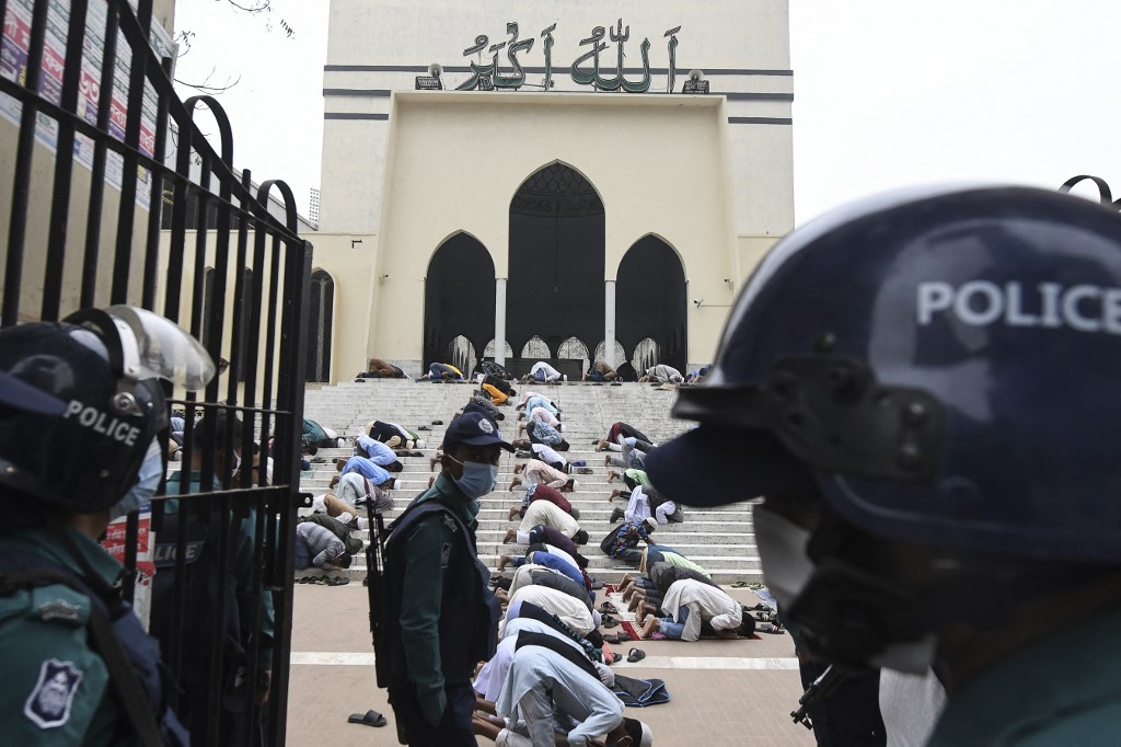 Police stand guard as Muslims pray at a Dhaka mosque on 11 December 2020 (AFP)