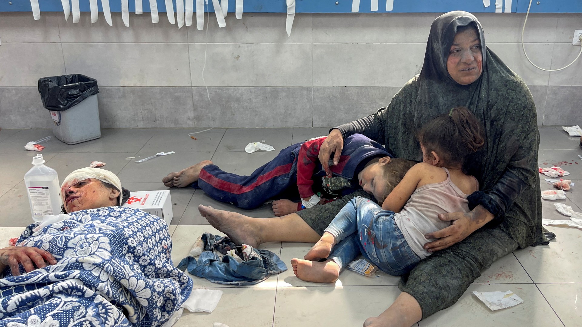 A Palestinian woman holds her children, who were wounded along with her in an Israeli strike, at Shifa hospital in Gaza City, October 23, 2023. REUTERS