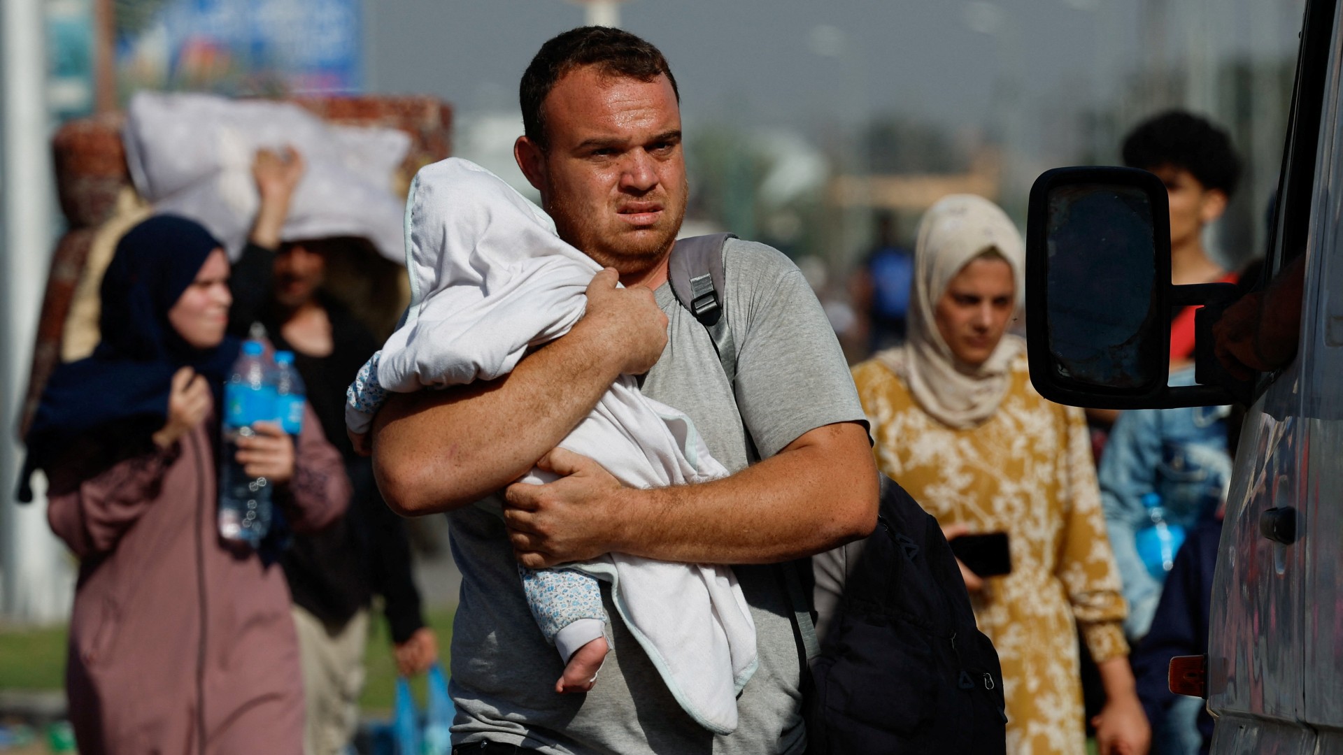 A man carries a child as Palestinians fleeing north Gaza walk towards the south