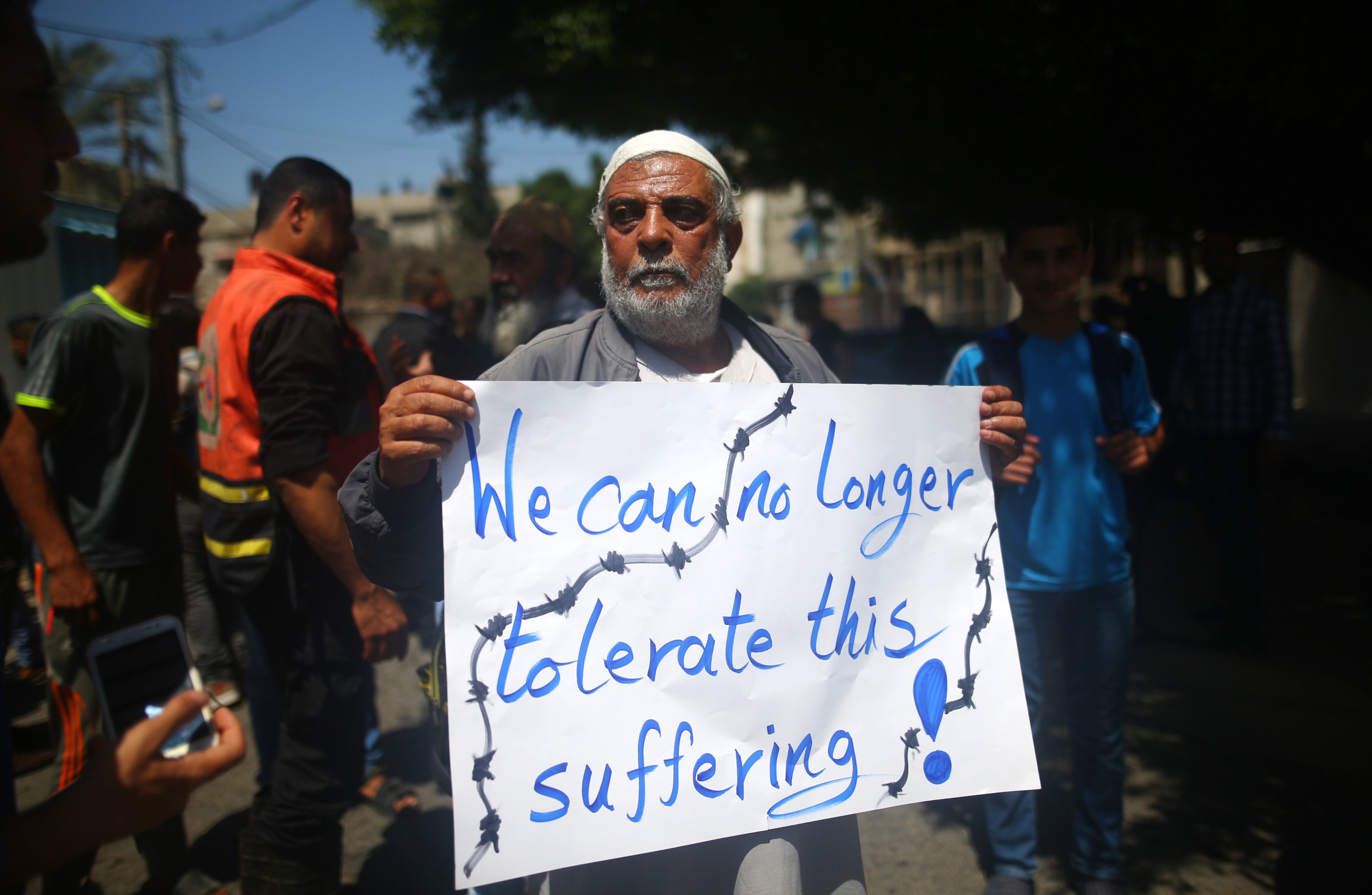 Un Palestinien dont la maison a été détruite pendant la guerre entre Israël et le Hamas à l’été 2014 tient une banderole devant le Programme des Nations unies pour le développement (PNUD)