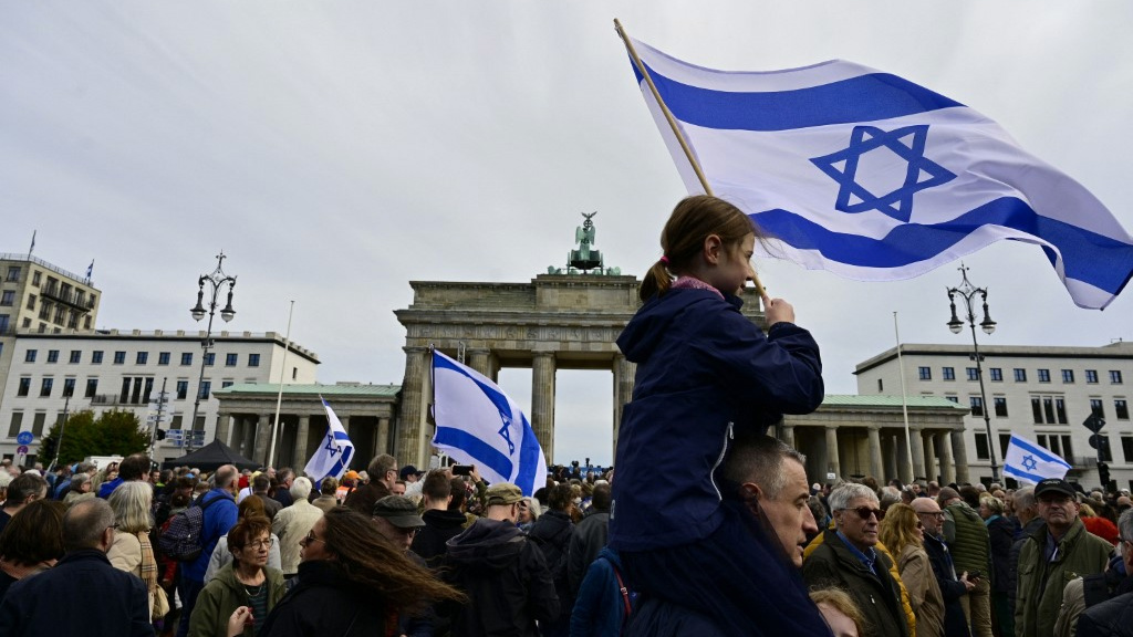 Demonstrators wave Israeli flags at a rally in Berlin on 22 October 2023 (AFP)