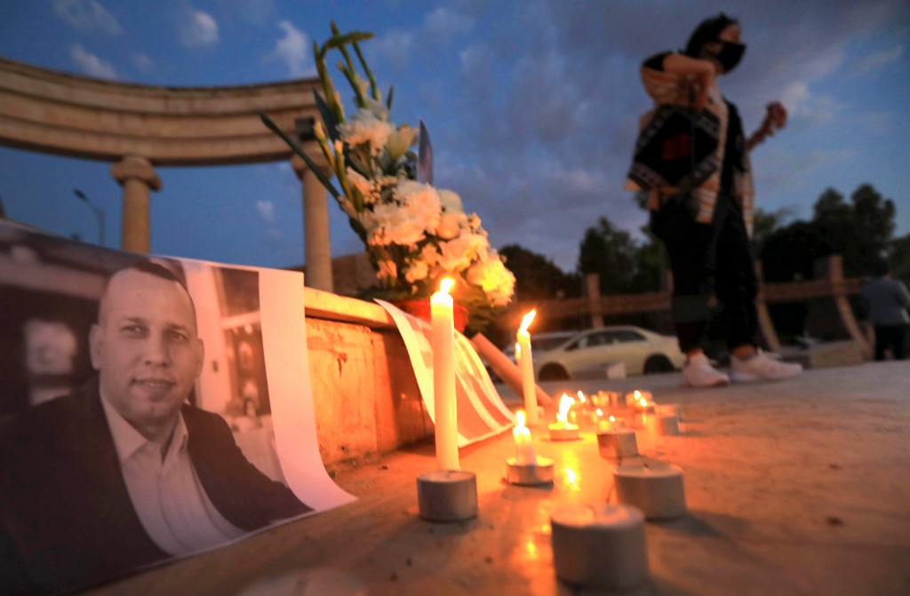 An Iraqi places a candle in front of a poster of slain Iraqi jihadism expert Hisham al-Hashemi, who was shot dead outside his house in the Iraqi capital, during a candlelight vigil in Arbil, the capital of the northern Iraqi Kurdish autonomous region, on July 11, 2020. 