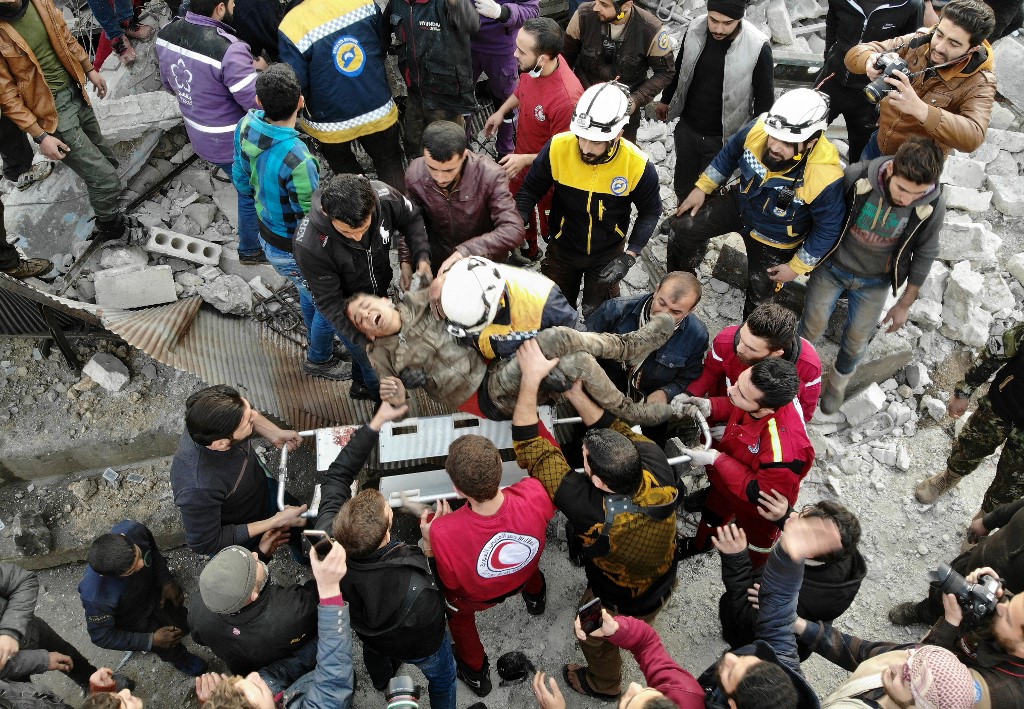 A drone picture taken in Idlib on 15 January shows members of the Syrian Civil Defence, also known as the White Helmets, carrying a boy out of rubble (AFP)