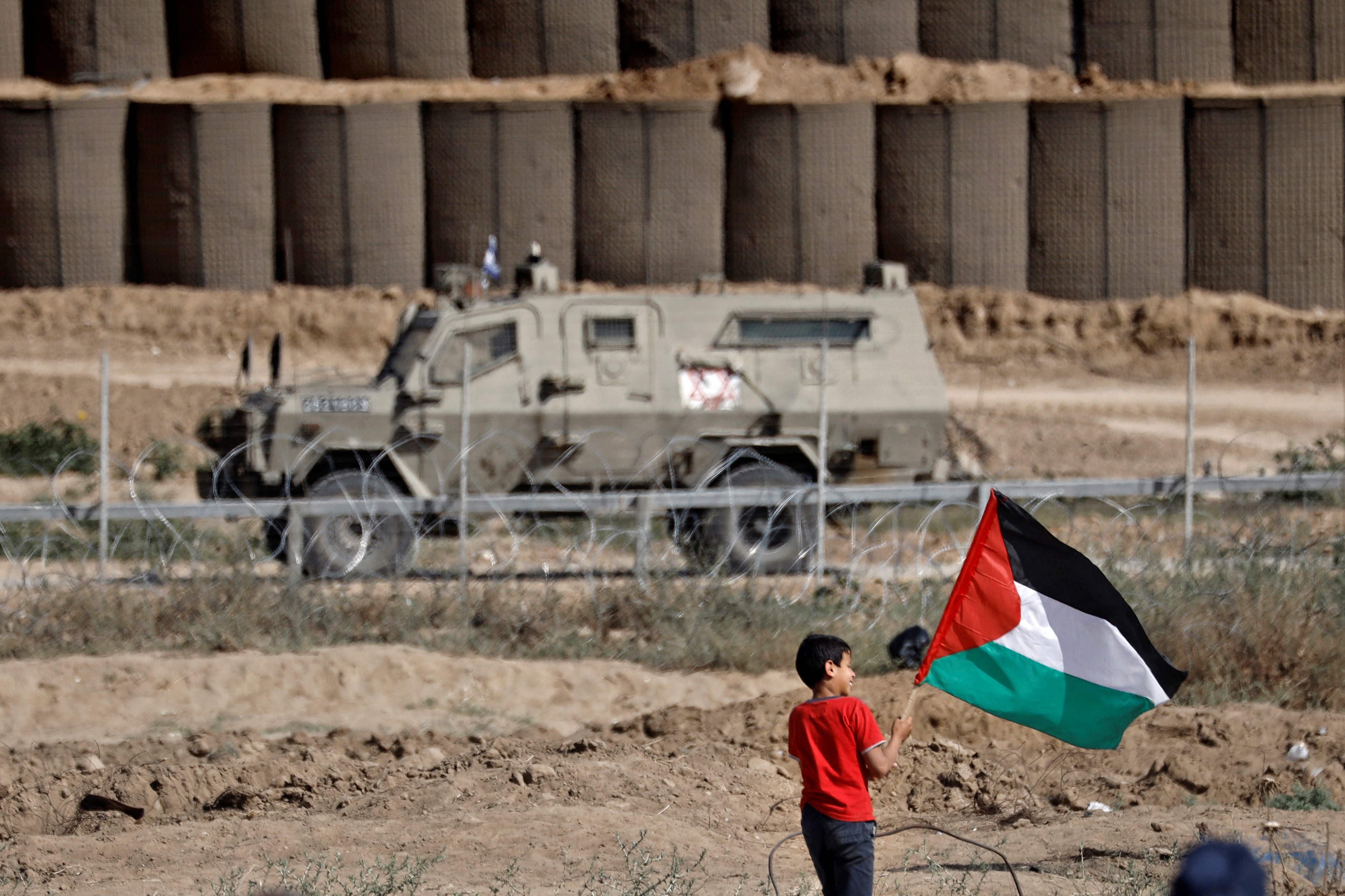 A Palestinian boy shows the national flag during clashes with Israeli forces following a protest marking the 71st anniversary of Nakba in El-Burej in the central Gaza Strip on 15 May (AFP)