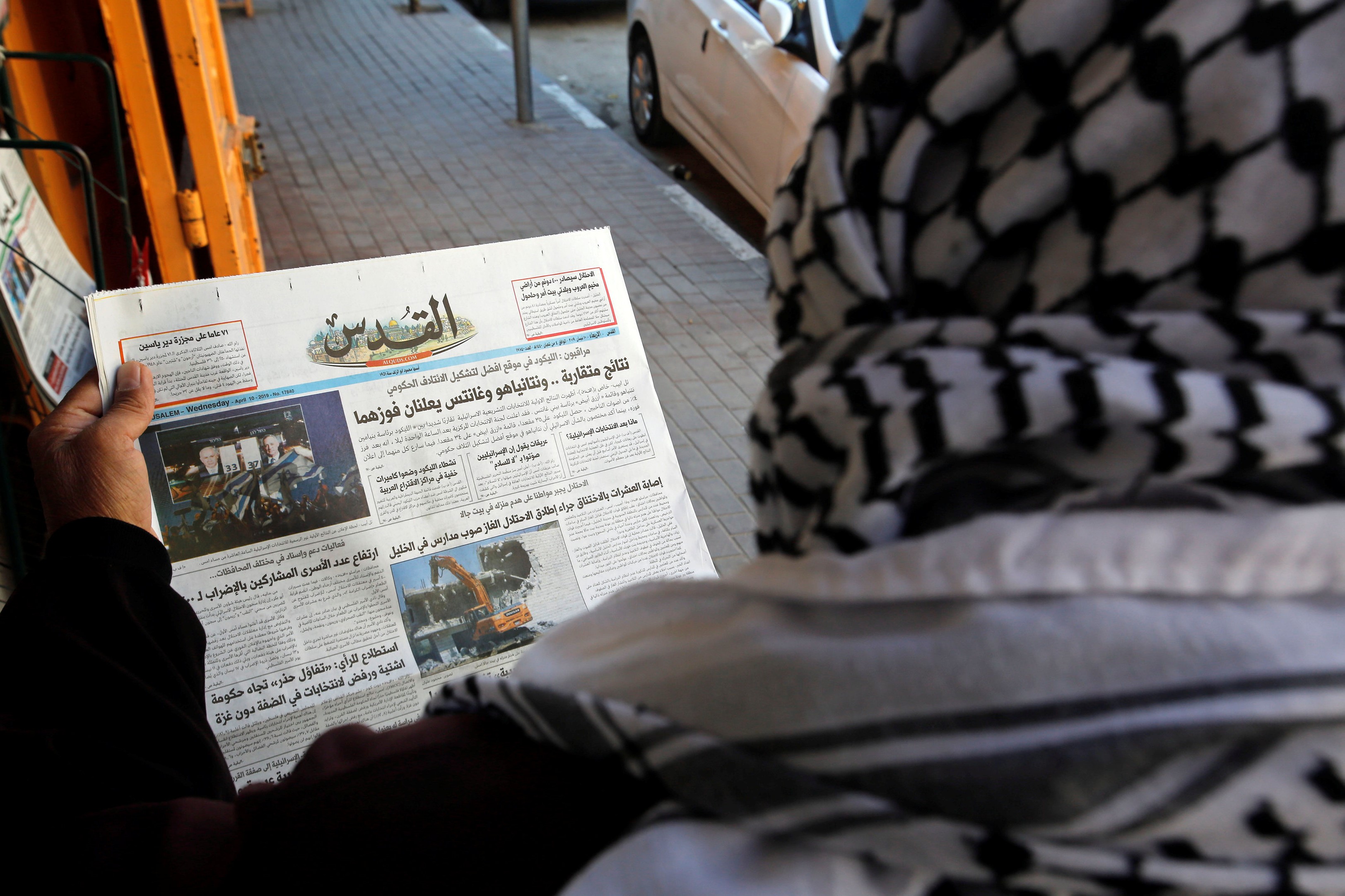 A Palestinian man reads a local newspaper with news of the Israeli election, in Hebron, in the Israeli-occupied West Bank on 10 April (REUTERS)