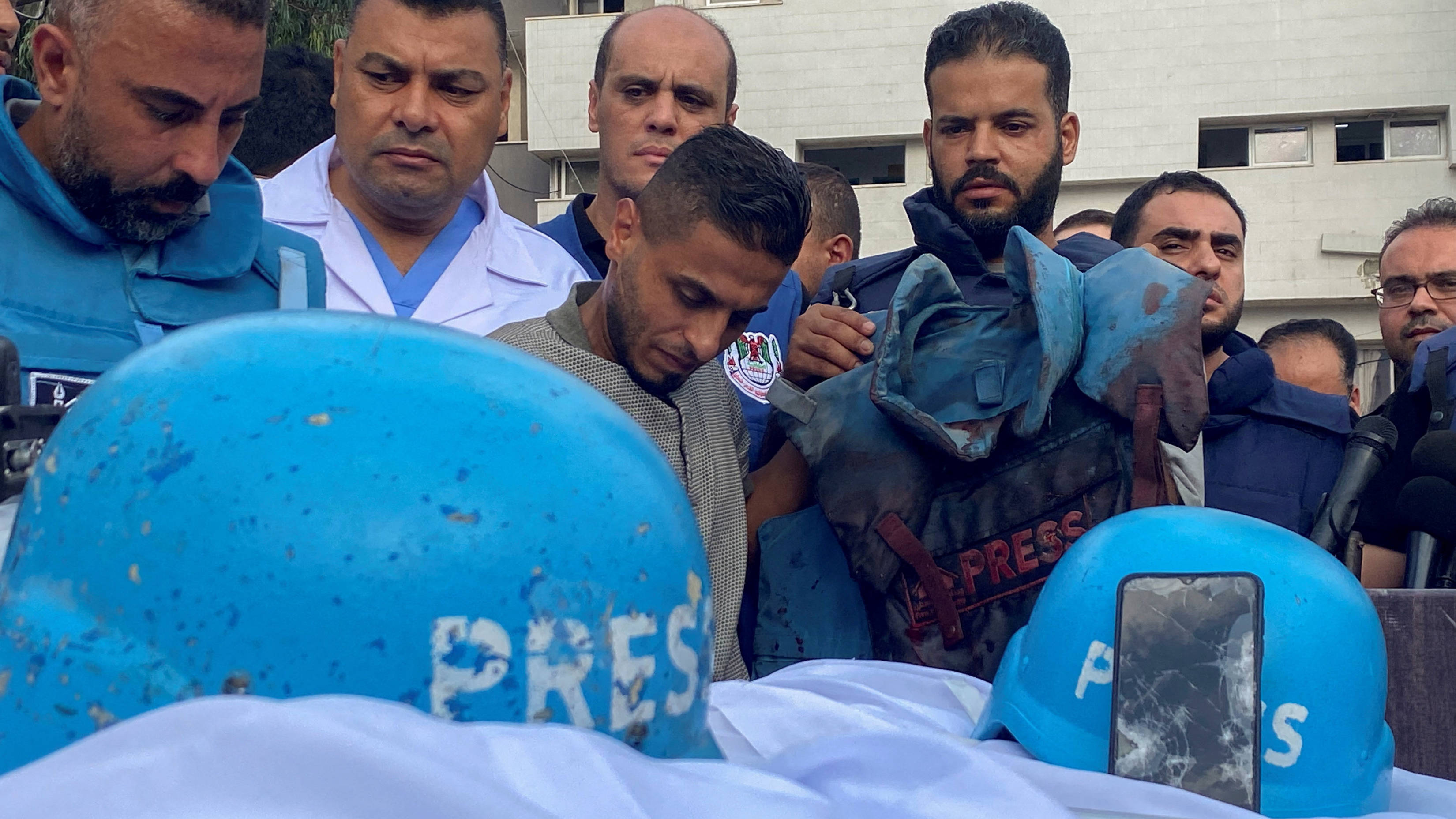 Colegas de periodistas palestinos junto a sus cuerpos en un hospital de la ciudad de Gaza después de su muerte en ataques aéreos israelíes, 10 de octubre de 2023 (Reuters)