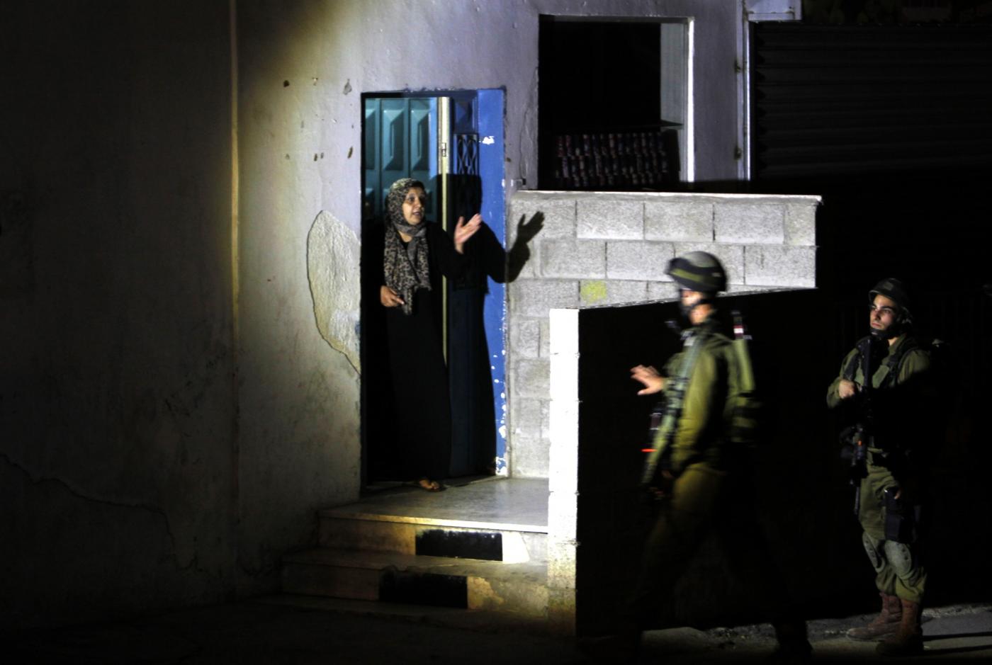 Israeli soldiers interrogate a Palestinian woman during a 2014 raid in the occupied West Bank (AFP)