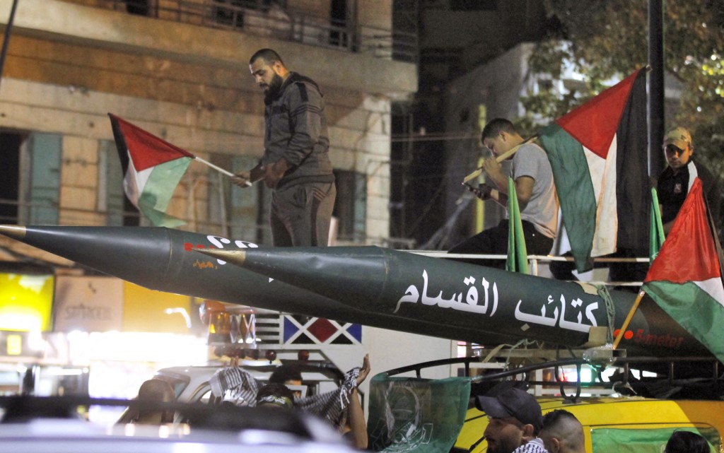Men parade with a model of a rocket labelled "Qassam Brigades” (Hamas’s armed wing) during a demonstration in southern Lebanon on 11 May 2021 (AFP)