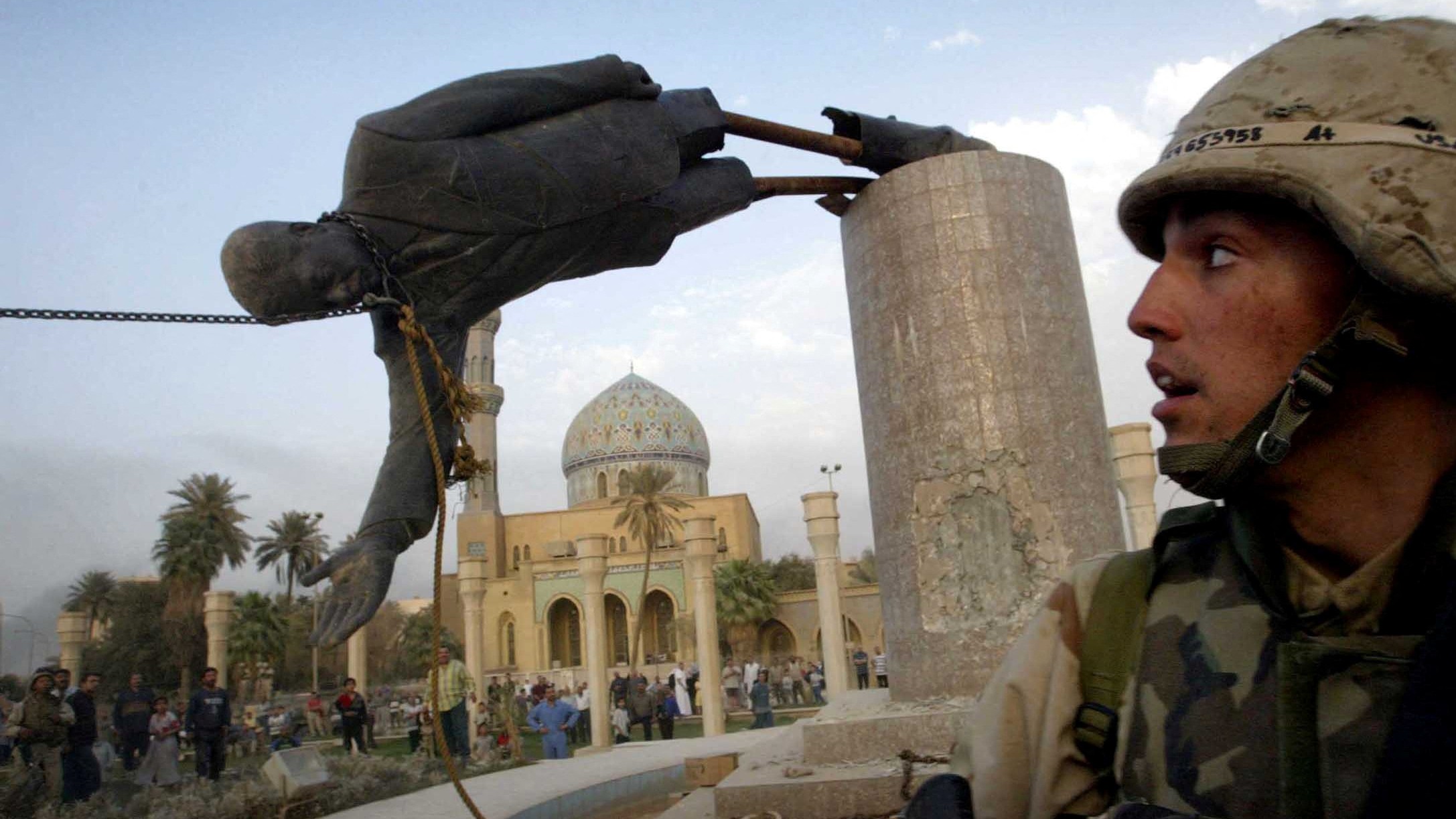 A US soldier watches as a statue of Iraq's President Saddam Hussein falls in central Baghdad, 9 April, 2003 (Reuters)