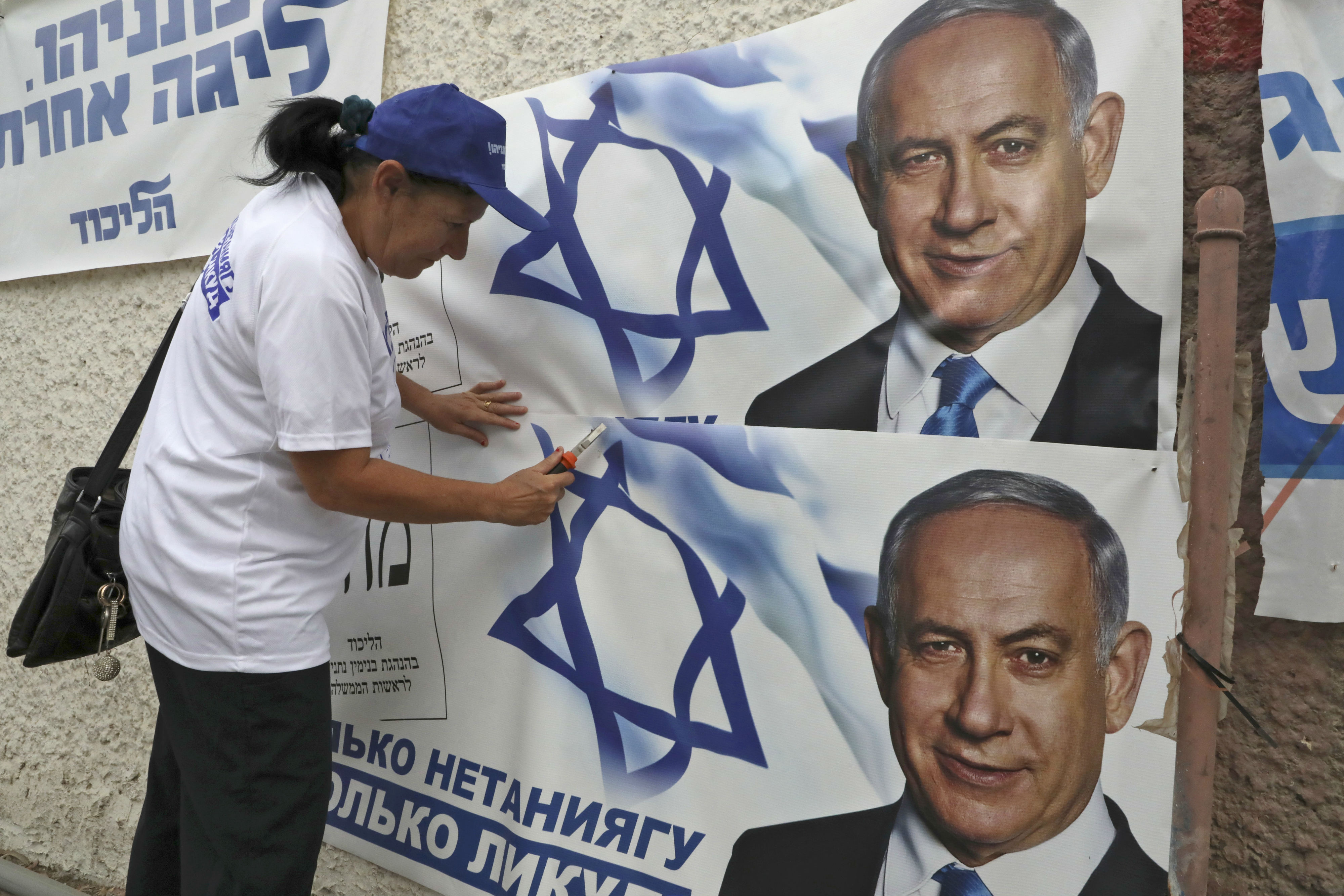 A woman places electoral banners for the Likud party showing chairman and Israeli Prime Minister Benjamin Netanyahu in the southern Israeli city of Beersheva (AFP)