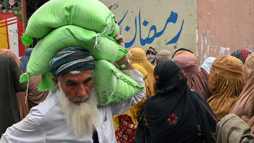 A man collects free bags of flour from a government distribution point in Peshawar, Pakistan, on 29 March 2023 (AFP)